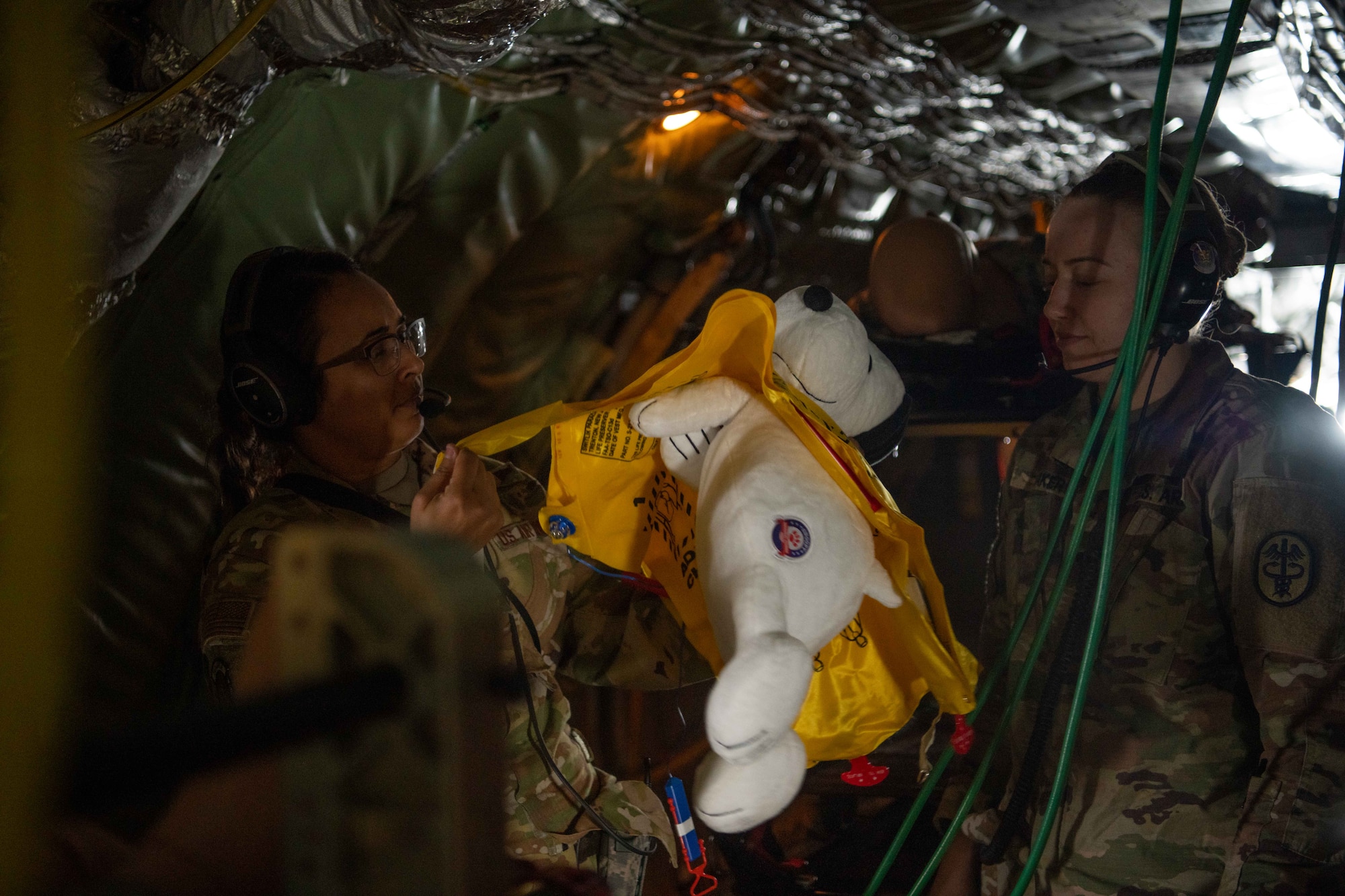 An Airman practices putting a life vest on a stuffed animal simulating a military working dog.