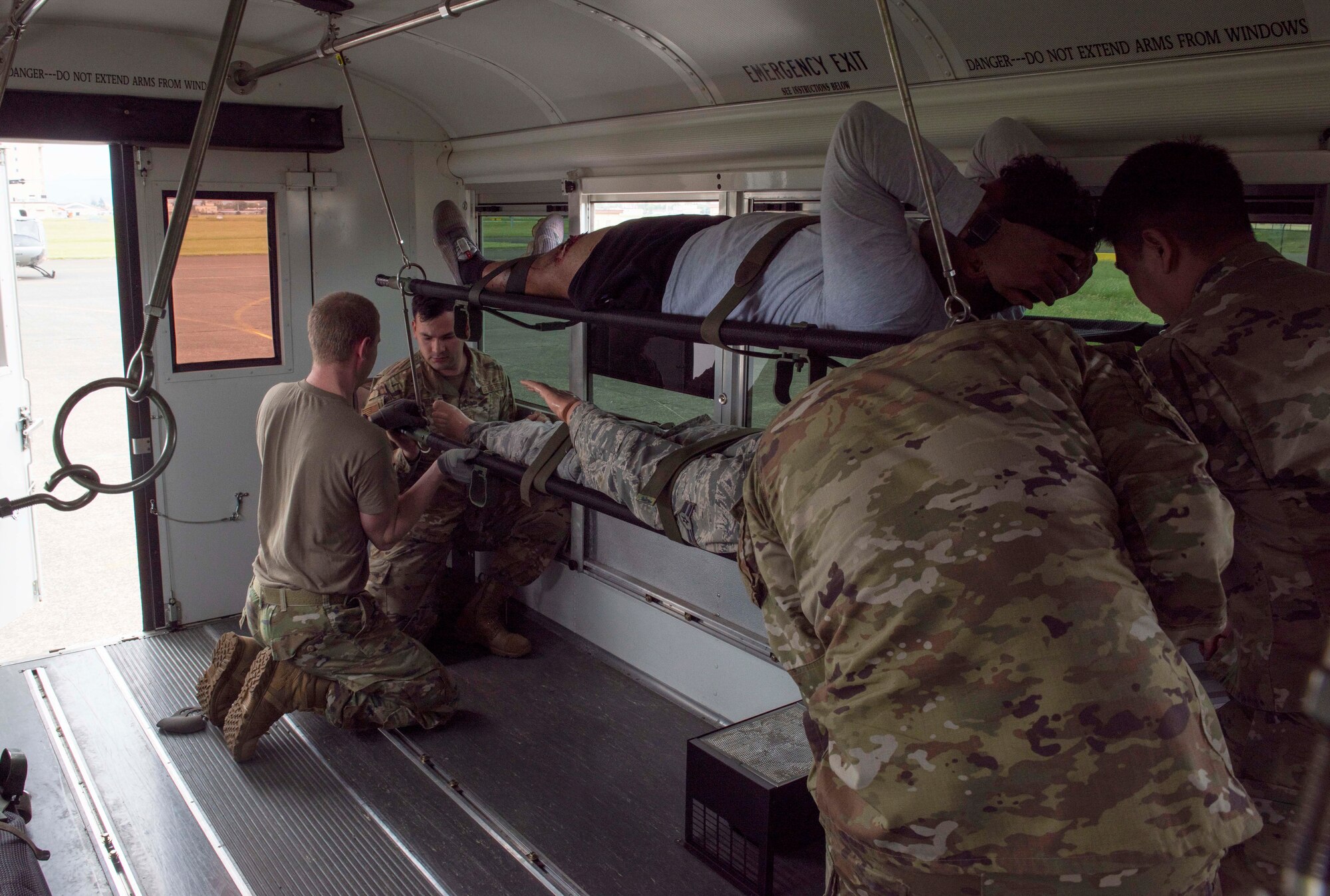 Airmen secure mock patients inside a transport bus