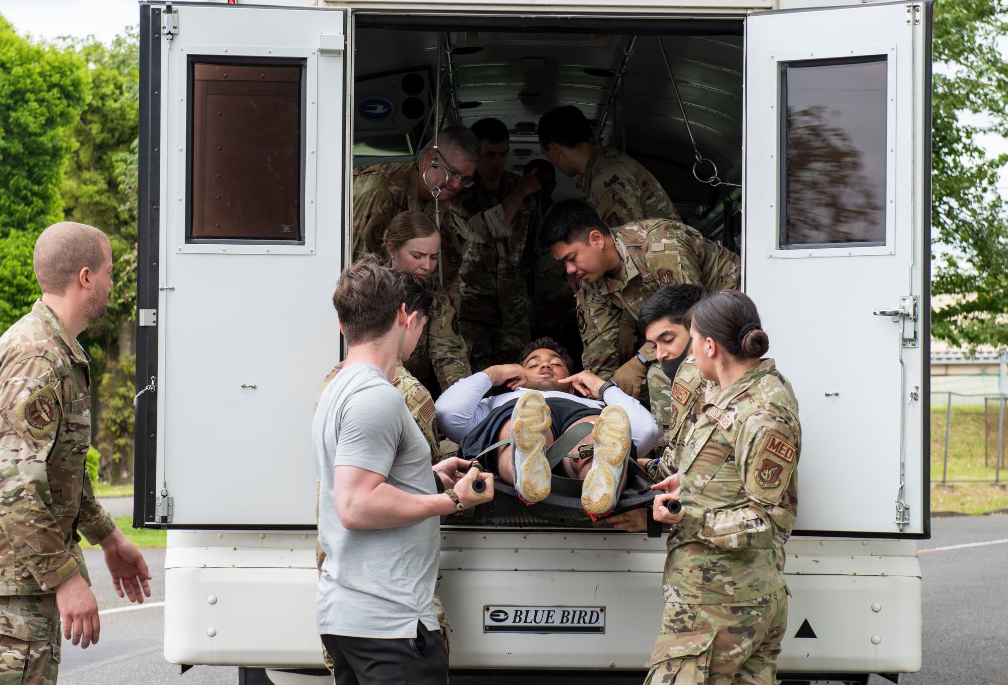 Airmen move a mock patient onto a transport bus