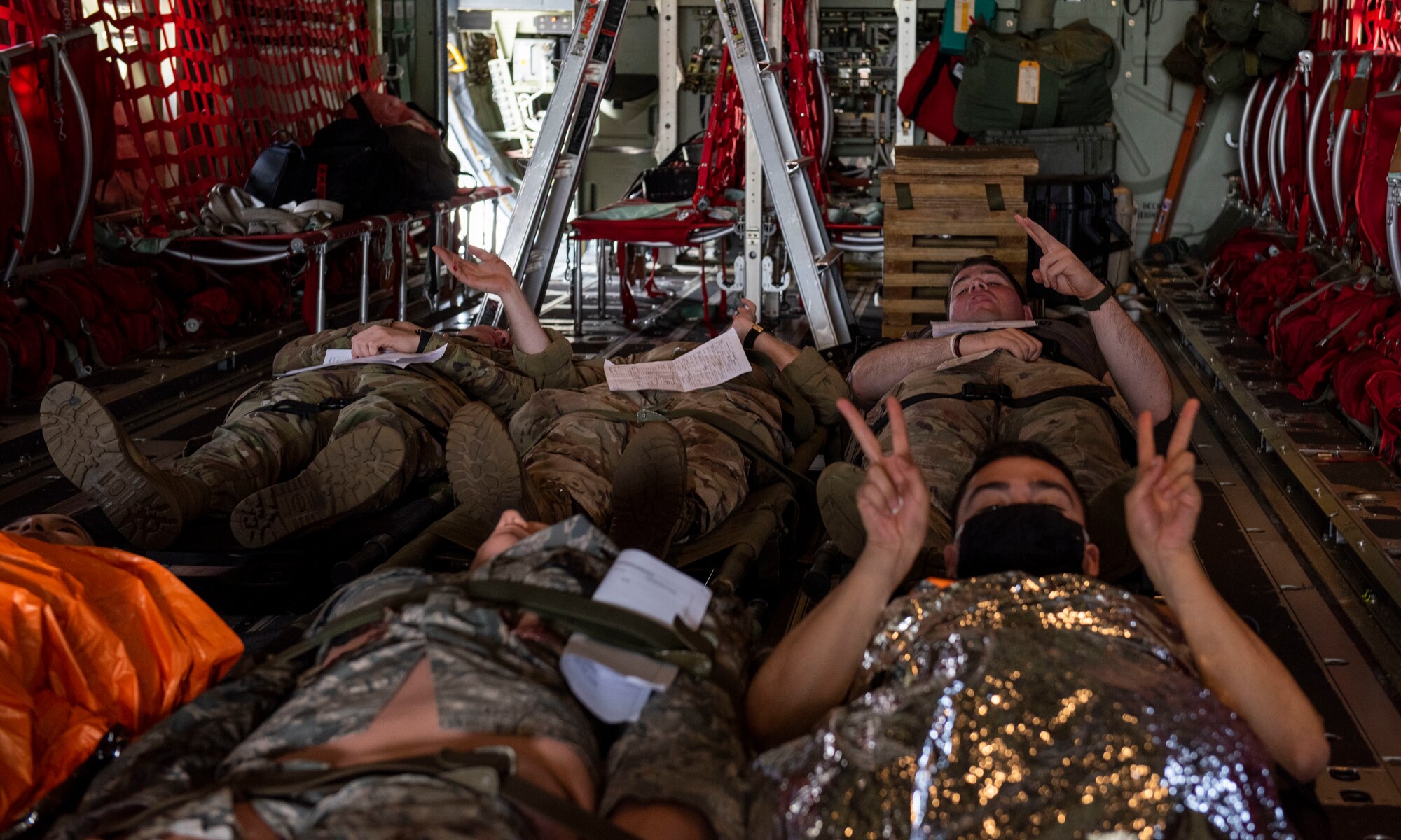 Mock patients wait on a C-130J Super Hercules for transportation