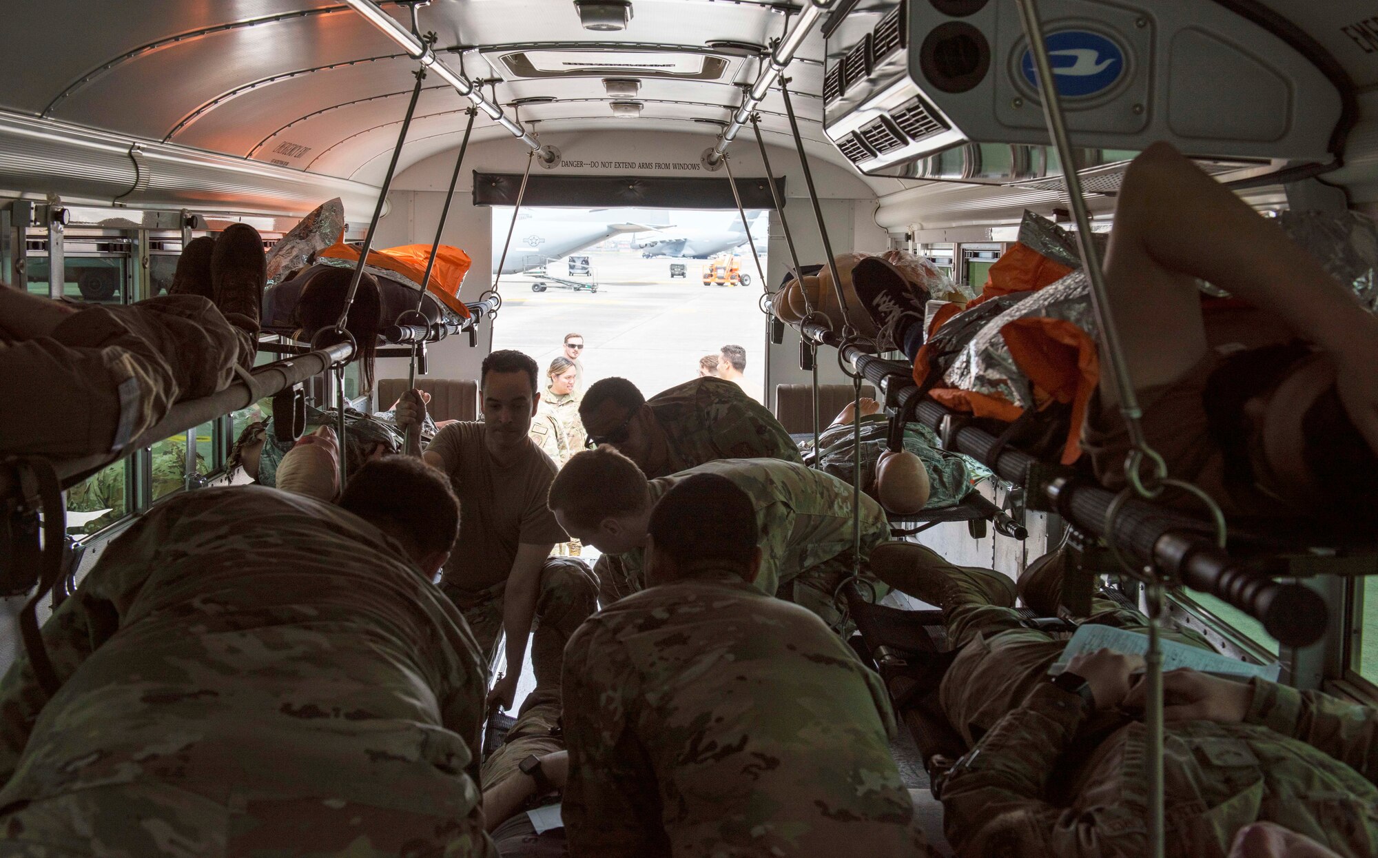 Airmen secure mock patients inside a transport bus