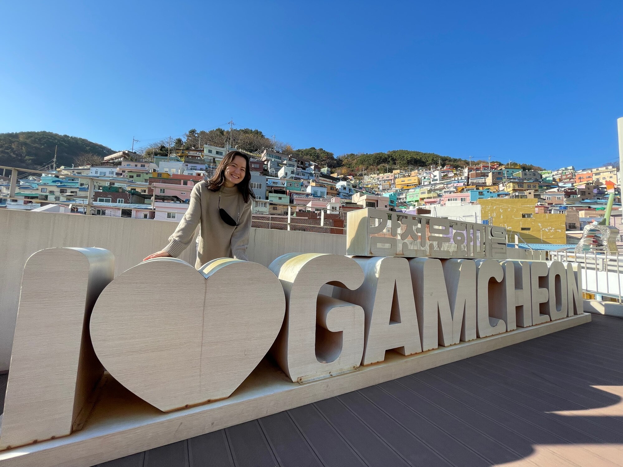 Abyy Fenn stands over a Gamcheon Village sign.