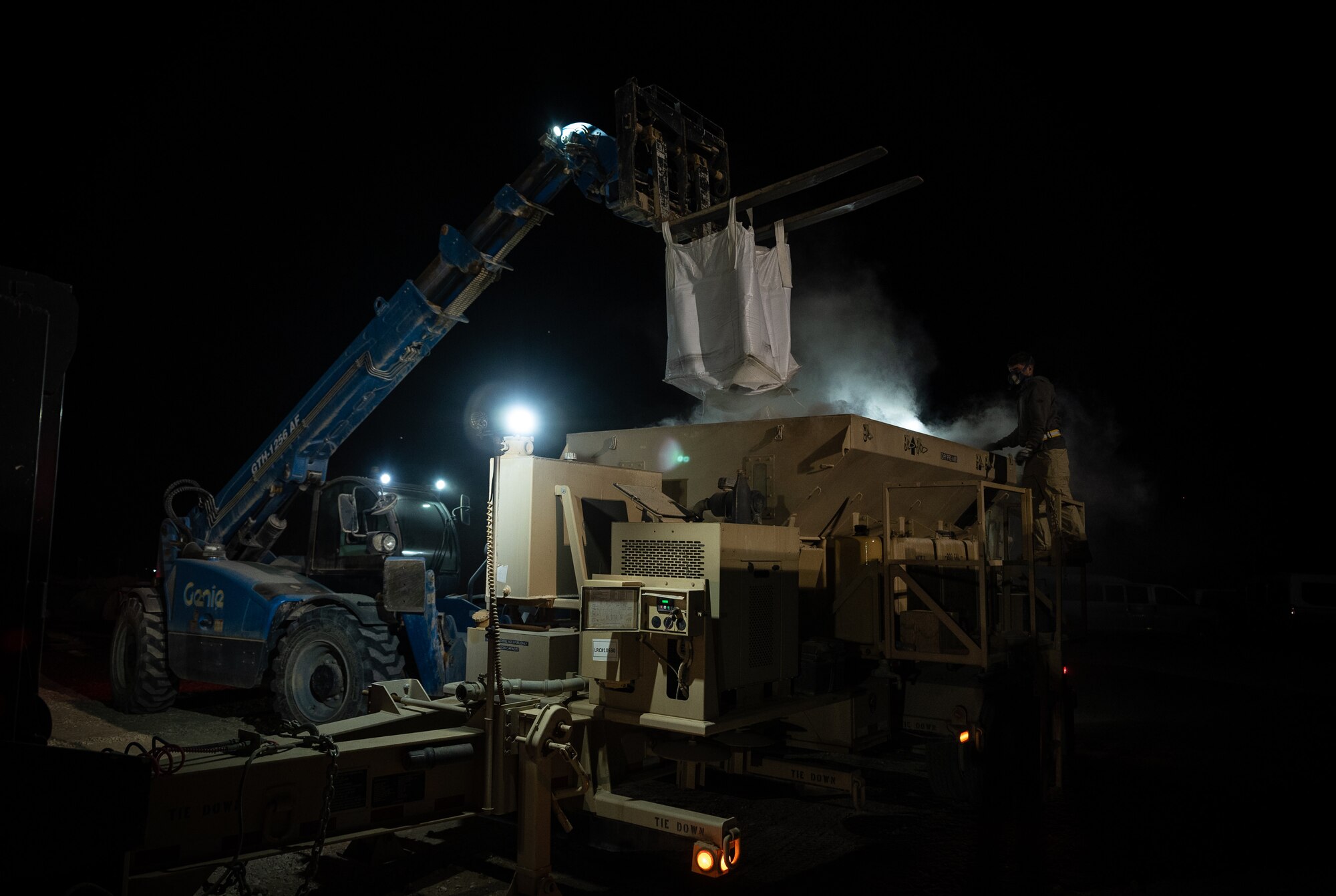 A bag of dry concrete empties into a mixer during a rapid airfield damage recovery exercise at an undisclosed location in Southwest Asia, May 12, 2022. RADR exercises test the ability of the 332d ECES to rapidly repair runways and runway support structures to recover and resume airfield operations after it has experienced significant damage. (U.S. Air Force photo by Master Sgt. Christopher Parr)