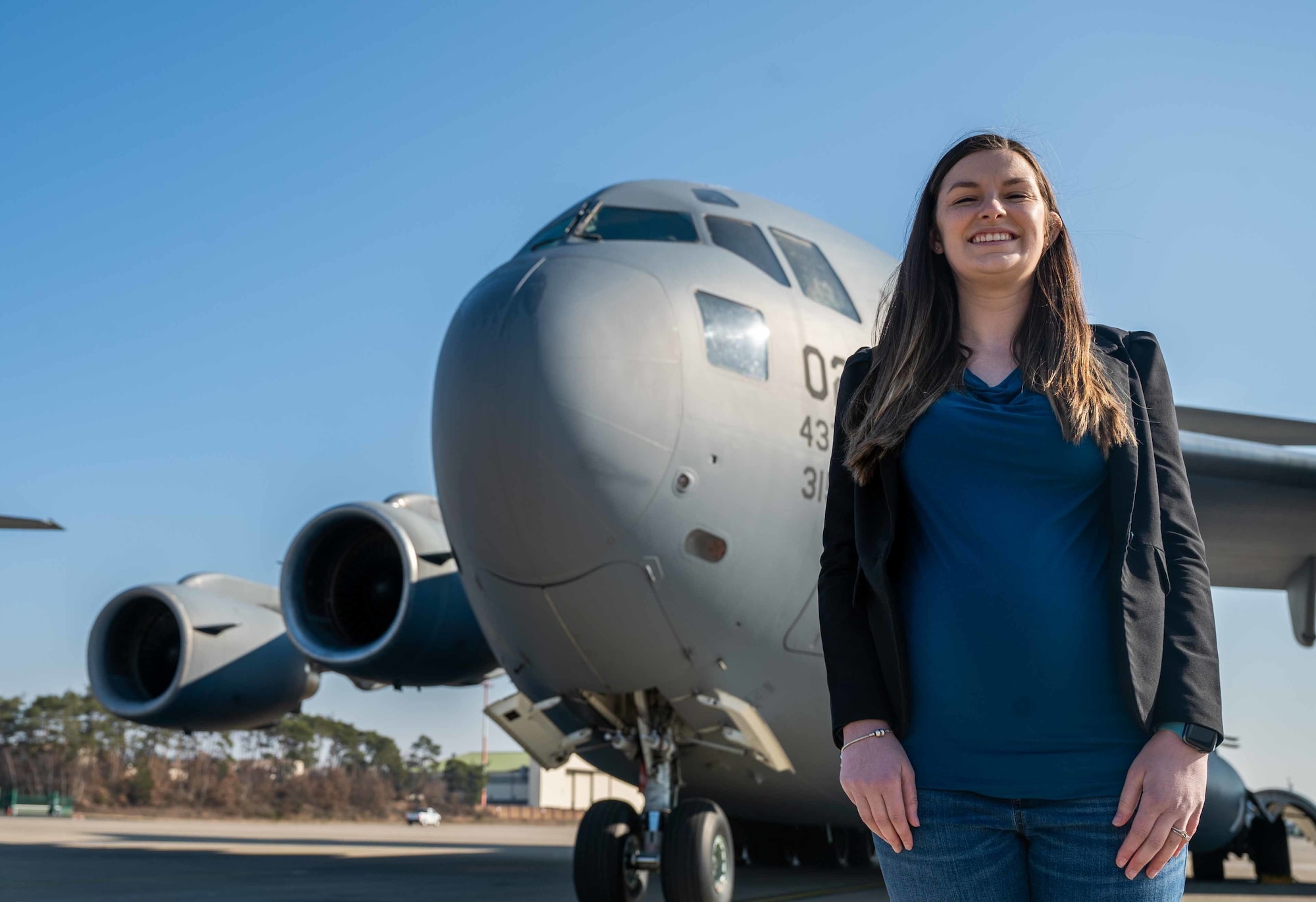 Caitlyn Chase, 521st Air Mobility Operations Wing key spouse, poses for a photo in front of a C-17 Globemaster III at Ramstein Air Base, Germany, Mar. 4, 2022. For her service, Chase was Air Mobility Command’s nominee for the Air Force level 2021 Joan Orr Air Force Spouse of the Year Award. (U.S. Air Force photo by Senior Airman Faith Schaefer)