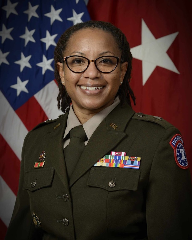 Female Soldier in her dress uniform standing in front of the American flag.