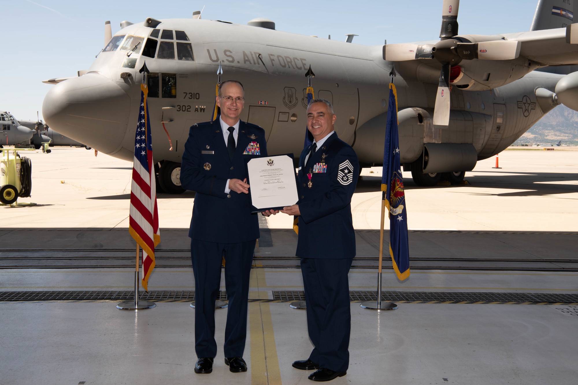 Col. Christopher Zidek, 302nd Airlift Wing commander, presents Chief Master Sgt. Kahn Scalise, 302nd Airlift Wing command chief, with a retirement certificate during Scalise’s retirement ceremony.