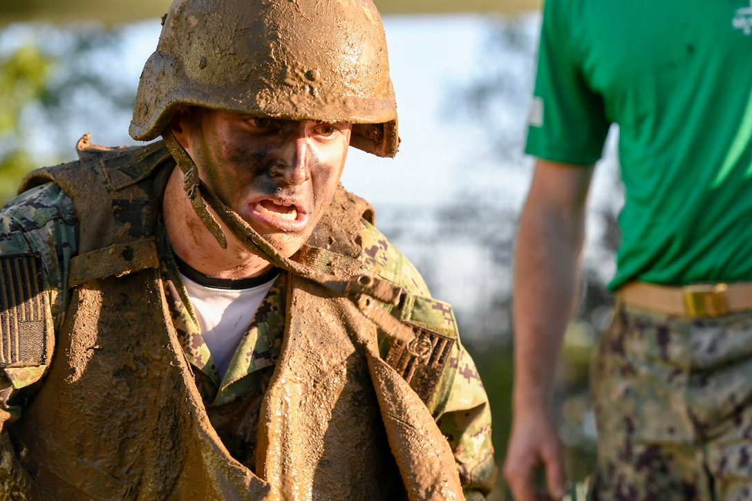 A Navy midshipman completes an obstacle in the mud.