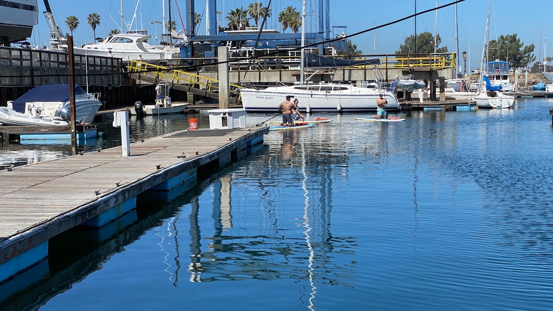 RSM kneels on paddle board near dock.