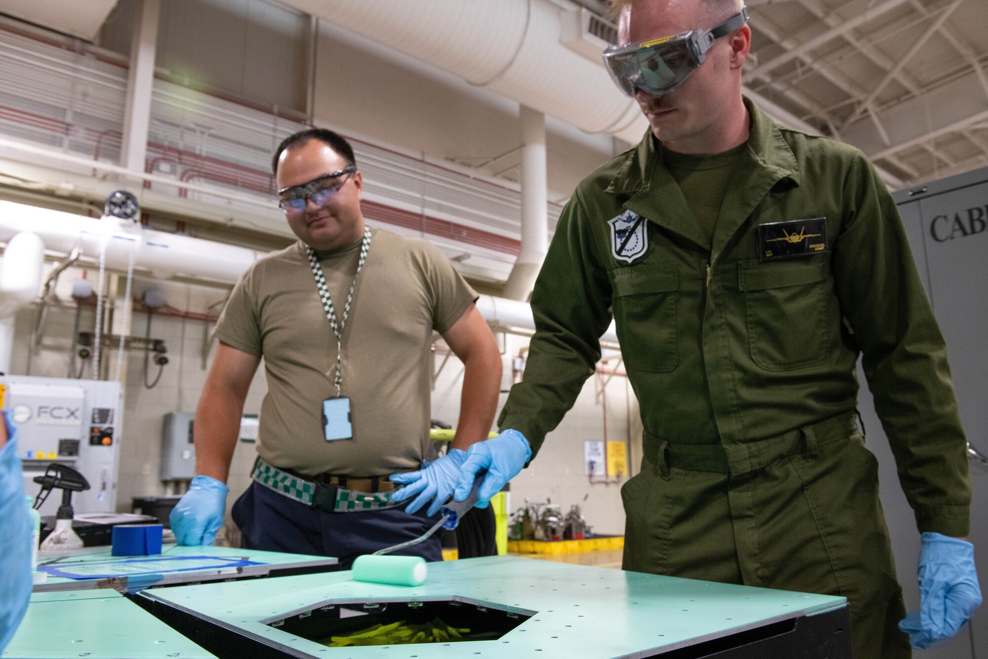 U.S. Air Force Staff Sgt. Alex Saling, 308th Aircraft Maintenance Unit dedicated crew chief (left), instructs U.S. Marine Corps Sgt. Jared Stevison, Marine Fighter Attack Squadron 214 avionics technician (right), on procedures for application of low observable primer May 9, 2022, at Luke Air Force Base, Arizona.