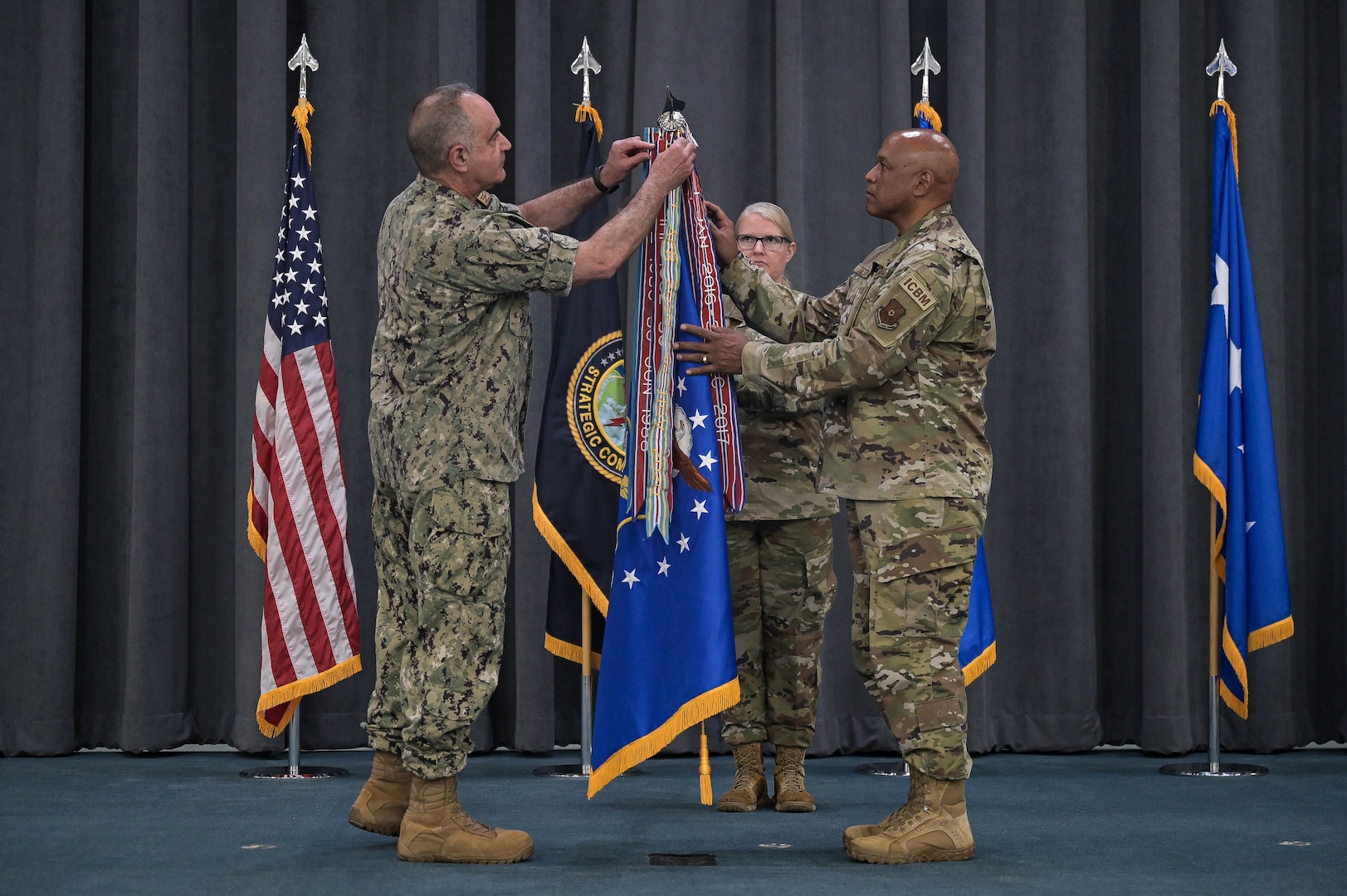 Adm. Charles Richard, left, U.S. Strategic Command commander, and Gen. Anthony Cotton, right, Air Force Global Strike Command commander, pin the Joint Meritorious Unit Award ribbon on the Air Force flag at Barksdale Air Force Base, Louisiana on May, 18, 2022. The JMUA was given to AFGSC in recognition of the command’s efforts and achievements during the height of the COVID-19 pandemic. AFGSC ensured mission success across three intercontinental ballistic missile wings and 495 remote facilities across the nation’s northern-tier bases, enabling U.S. Strategic Command to meet mission readiness capabilities. (U.S. Air Force photo by Senior Airman Jonathan E. Ramos)