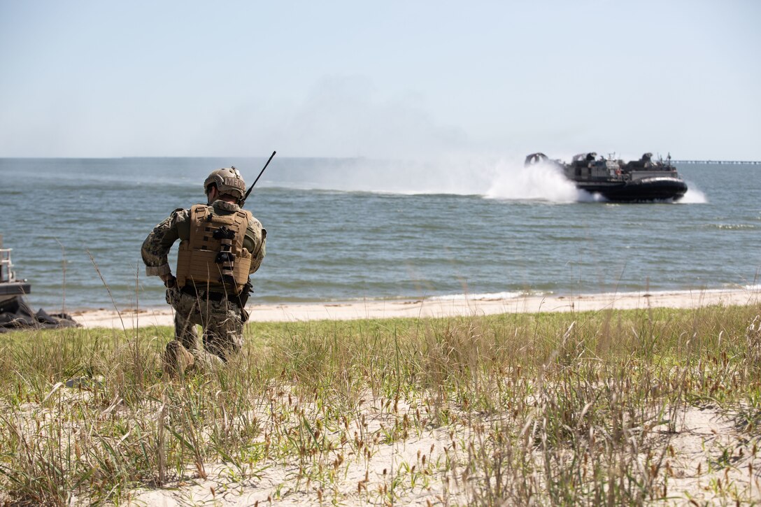 U.S. Navy Hospital Corpsman Second Class Matthew Giannascoui, a corpsman with Beachmaster Unit 2, U.S. 2nd Fleet, Fleet Forces Command uses radio communication to contact approaching Landing Craft Air Cushion 88 at Joint Expeditionary Base Little Creek-Fort Story, May 18, 2022. LOADEX trains Marines and Sailors to generate combined expeditionary lethality through maritime logistical maneuvers involving amphibious watercraft. The overarching strategy of LOADEX is to reinforce naval integration between the Marine Corps and Navy, creating a rapidly deployable maritime defense in support of forward-deployed forces. (U.S. Marine Corps photo by Lance Cpl. Angel Alvarado)
