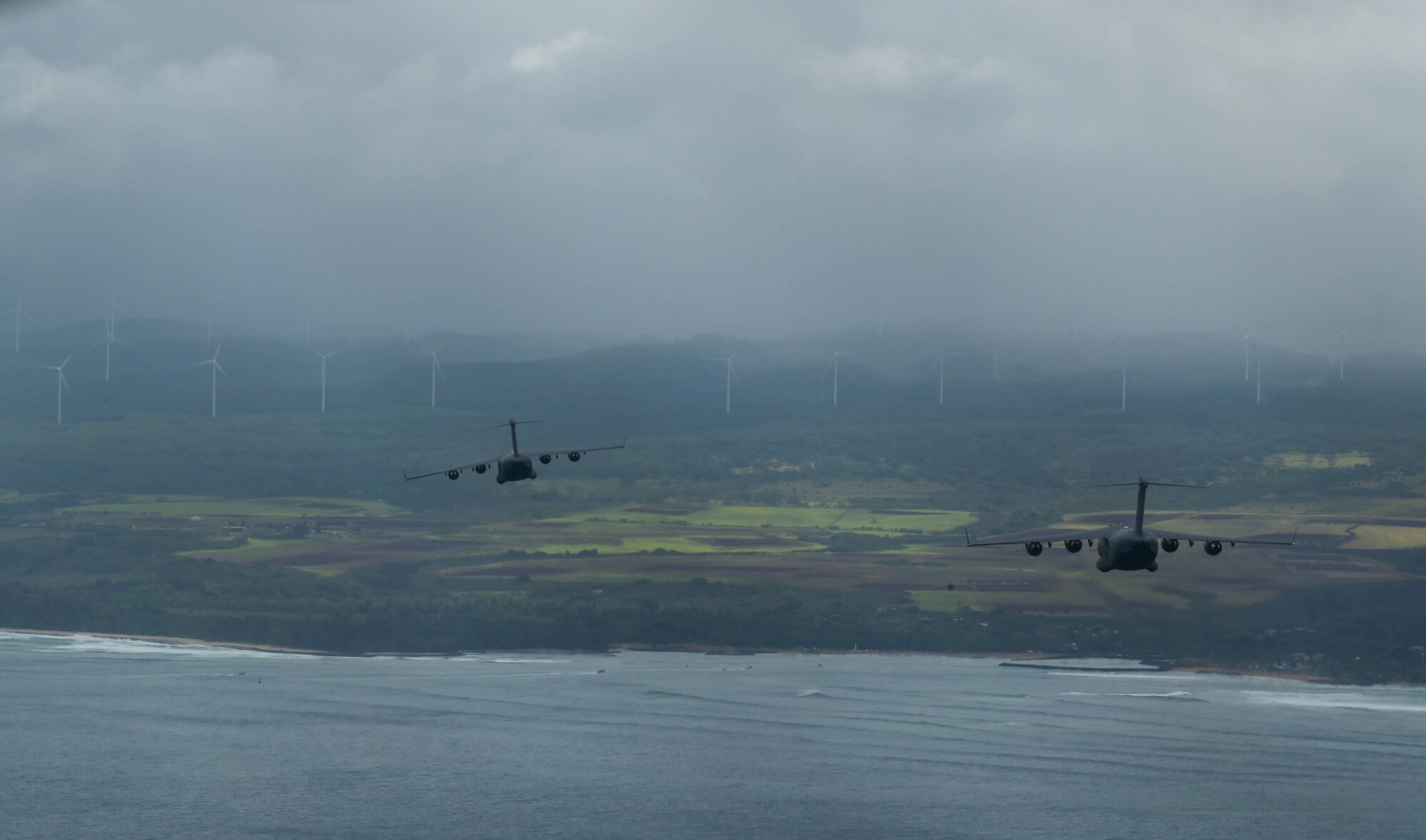 Two C-17 Globemaster IIIs from the Royal Australian Air Force and the U.S. Air Force fly in formation during an aerial maneuver training mission around the Hawaiian islands as part of Exercise Global Dexterity 2022 at Joint Base Pearl Harbor-Hickam, Hawaii, May 3, 2022. The RAAF and USAF conducted joint flying missions alongside each other and swapped aircrew members to better learn of each others’ procedures and techniques. (U.S. Air Force photo by Staff Sgt. Alan Ricker)