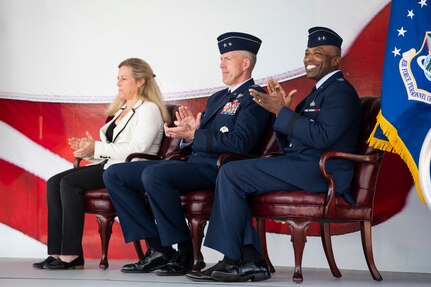 2 people sitting down in chairs clapping at ceremony