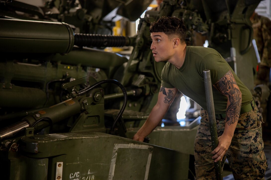 A Marine moves a large piece of military equipment.