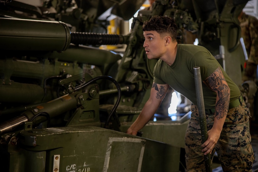 A Marine moves a large piece of military equipment.