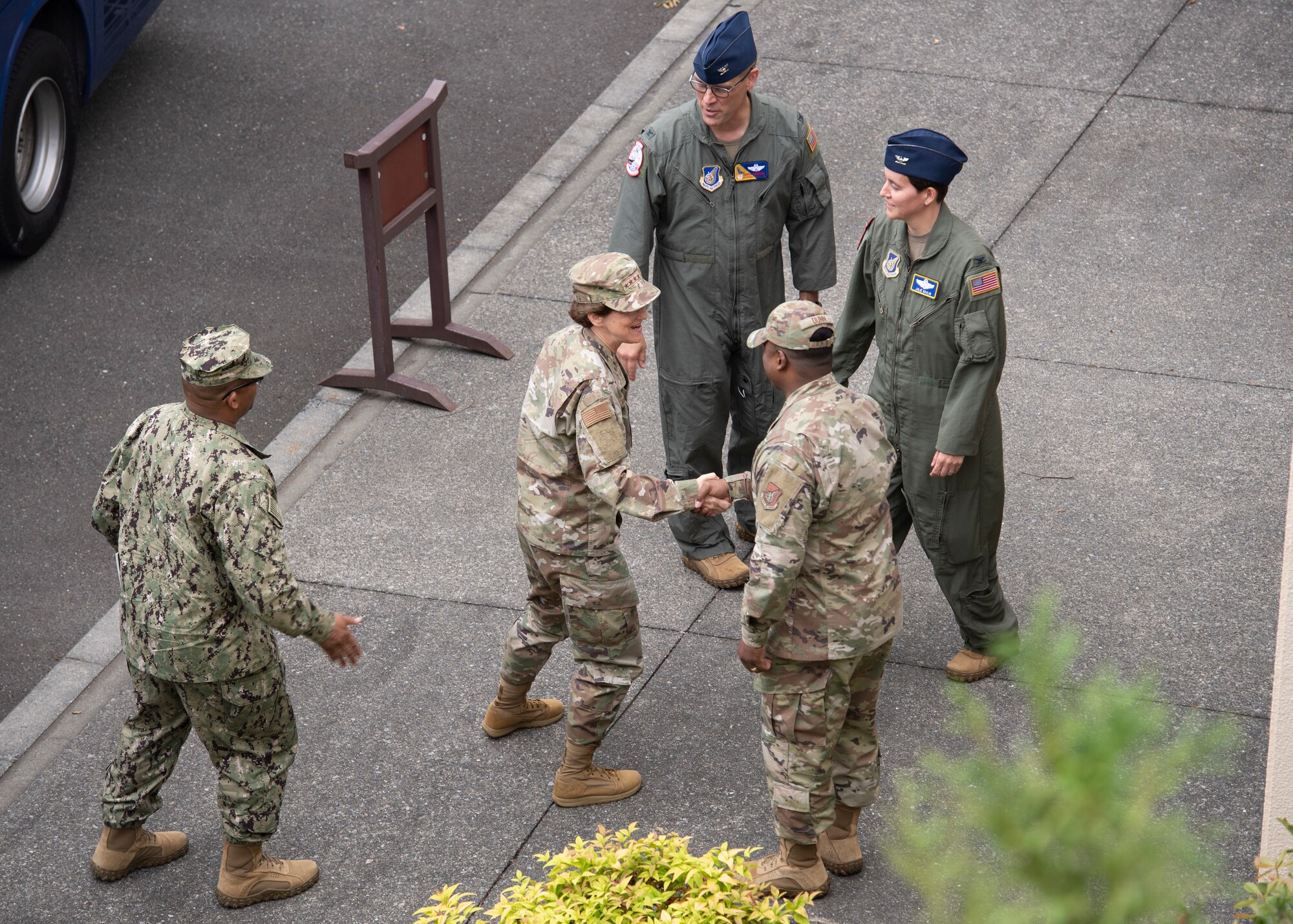 A top-down photo of a female general greeting base leaders