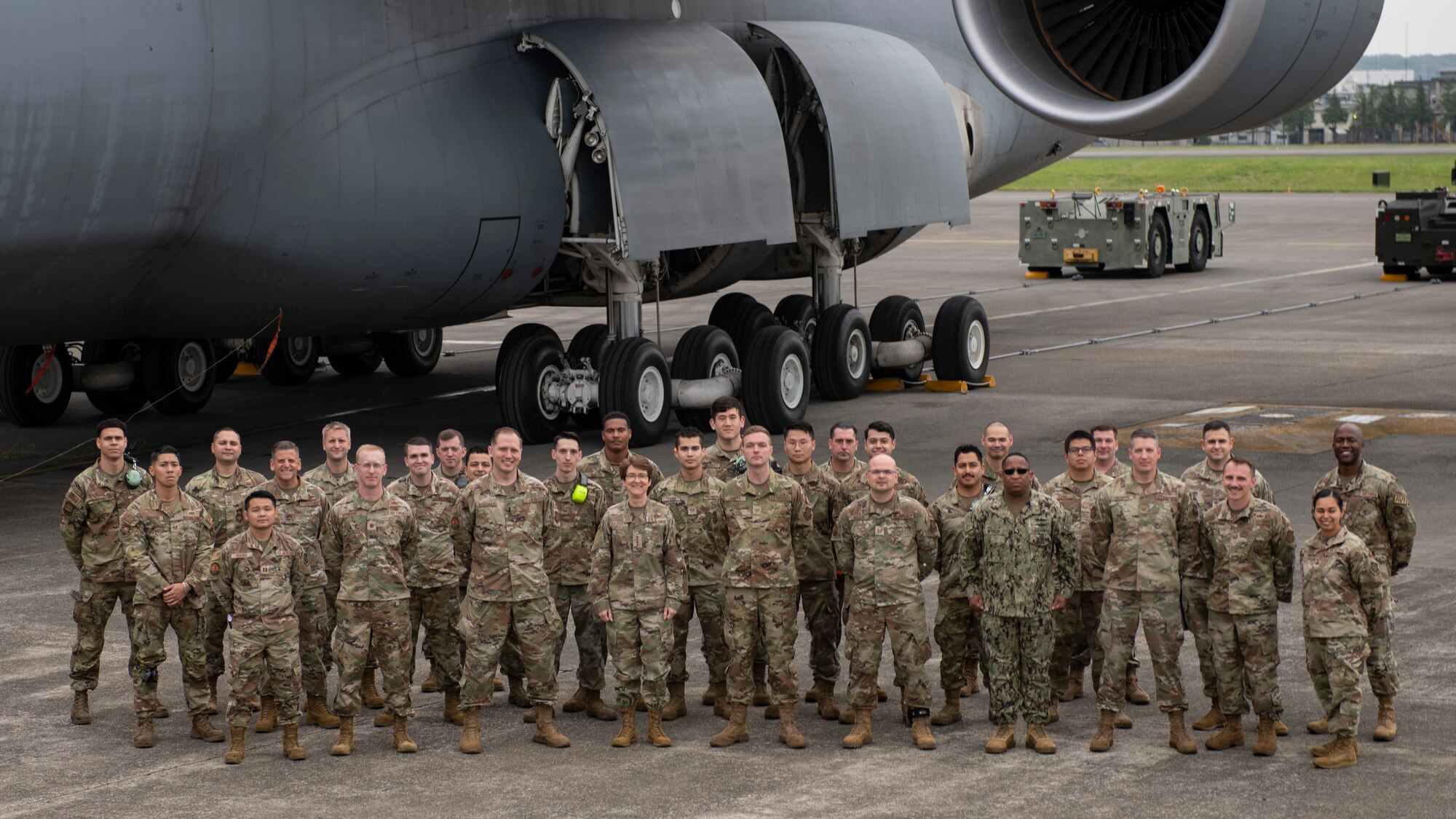 A group photo of about 100 Airmen standing in front of a giant cargo aircraft