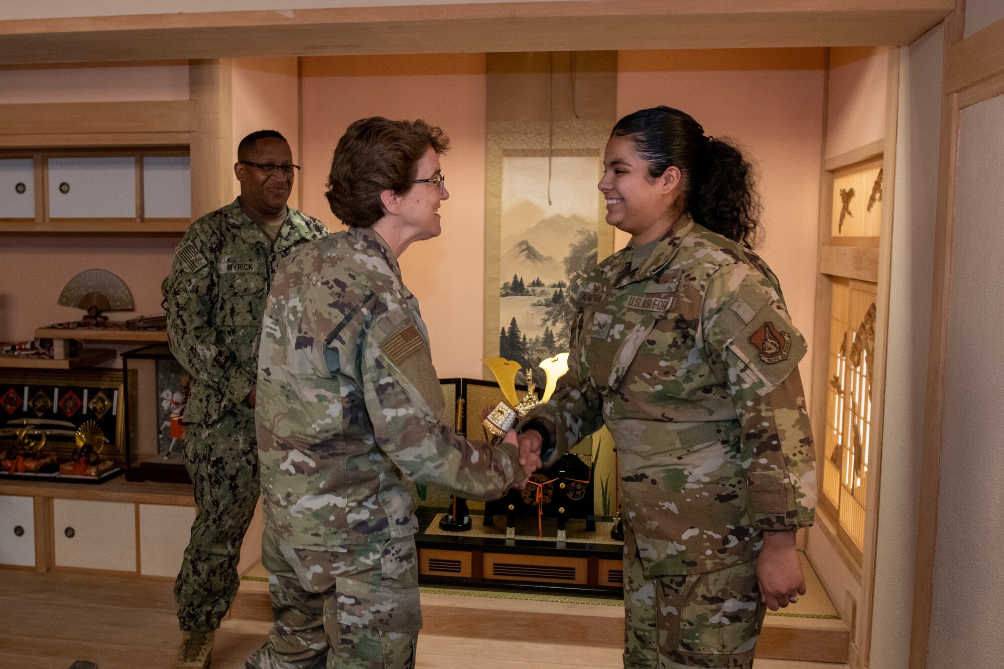 A female general shakes hands with a female Airman
