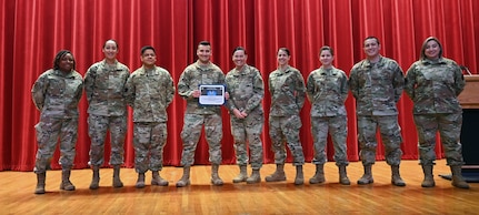 Senior Airman Gregory Martinez, 50th Network Warfare Squadron, stands with 960th Cyberspace Wing first sergeants after accepting the Diamond Sharp Award during an enlisted call May 14, 2022, at the Bob Hope Performing Arts Center, Joint Base San Antonio-Lackland, Texas. The Diamond Sharp Award is presented to Airmen who exceed the standard to meet the Air Force mission. (U.S. Air Force photo by Kristian Carter)