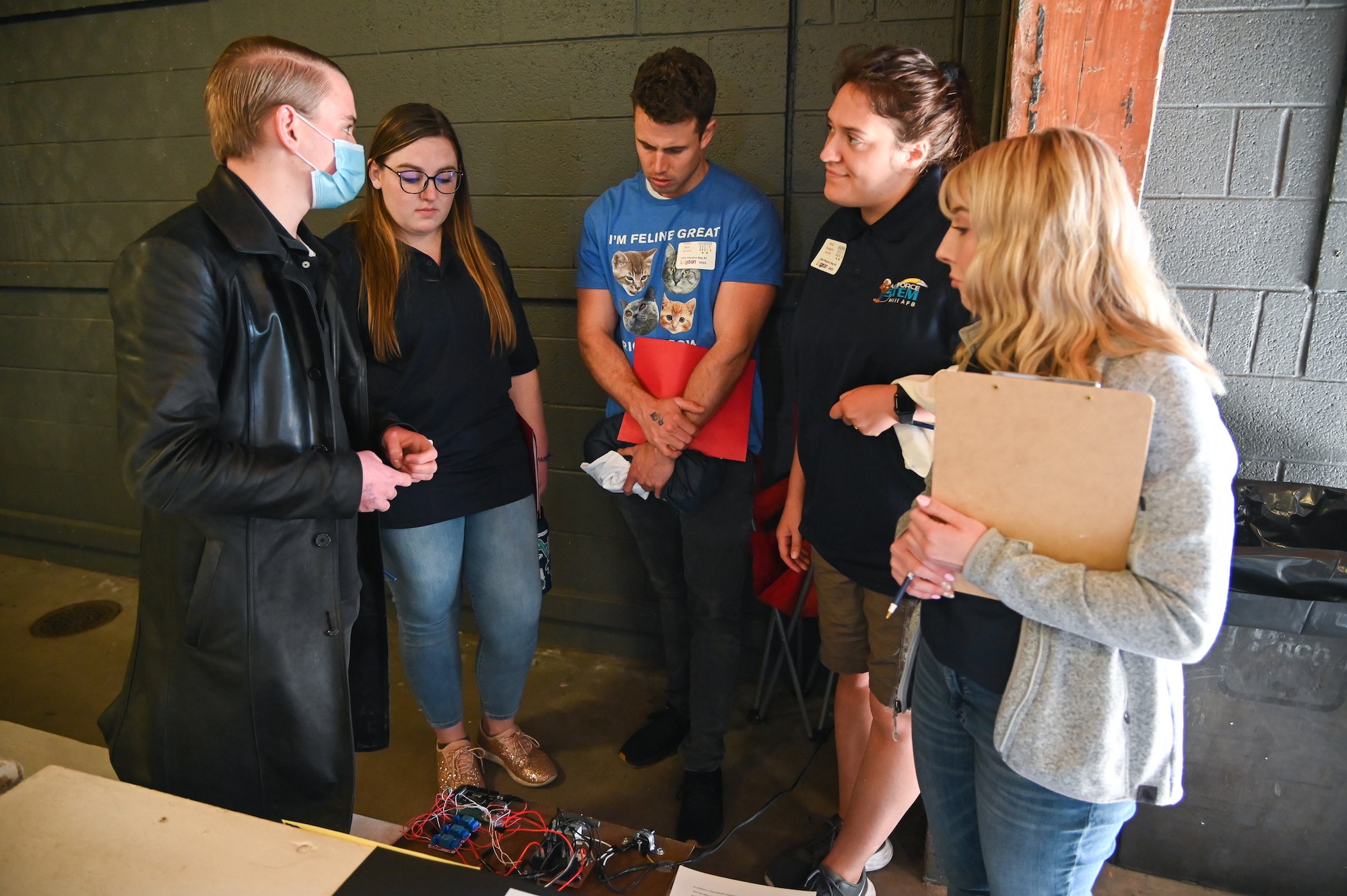 (right to left) Delaney Burton, Emily Togaga'e, Colby Bird, and Kristen Newbury, listen to a student's physics project presentation during Physics Day May 13, 2022, at Lagoon amusement park in Farmington, Utah.