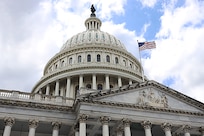 View of the U.S. Capitol dome, with waving American flag.