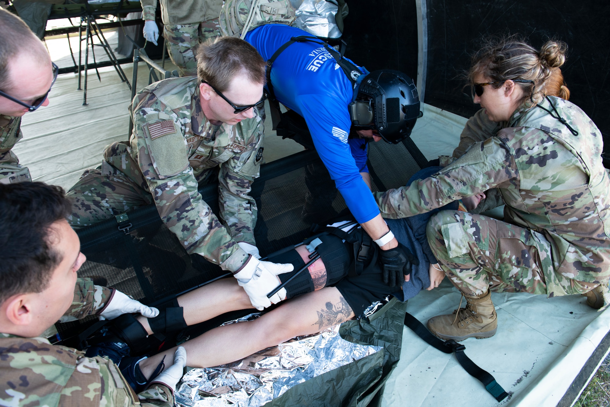 Airmen and civilians conduct simulated medical procedures on a simulated patient.