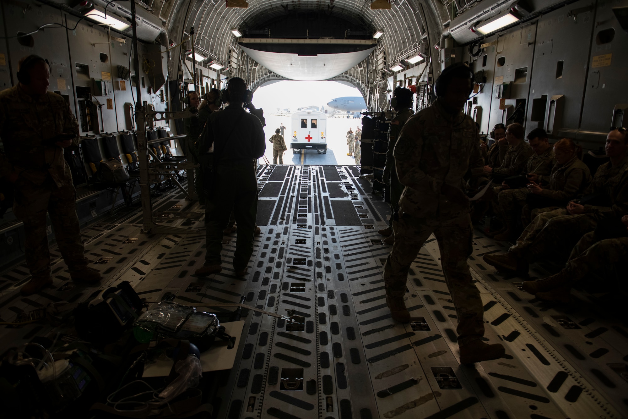 Airmen in an aircraft with shuttle at cargo entrance.