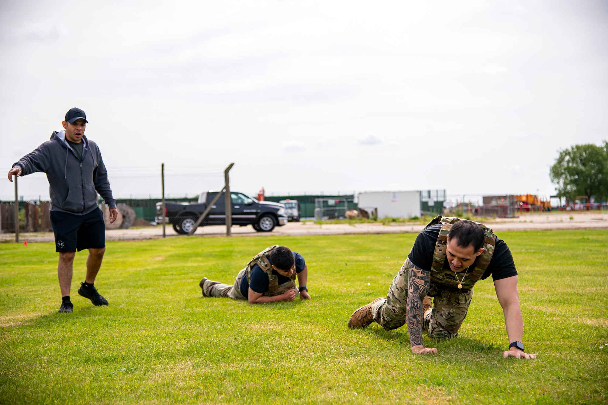U.S. Air Force Staff Sgt. Noel Rillona, right, 423d Security Forces Squadron flight trainer, and Senior Airman Adrien Tovar, center, 423d SFS trainer, low crawl as part of a defender challenge at RAF Alconbury, May 18, 2022. Airmen, civilians and local law enforcement participated in the challenge, held in honor of National Police Week, to pay homage to those who gave their lives in the line of duty. (U.S. Air Force photo by Staff Sgt. Eugene Oliver)