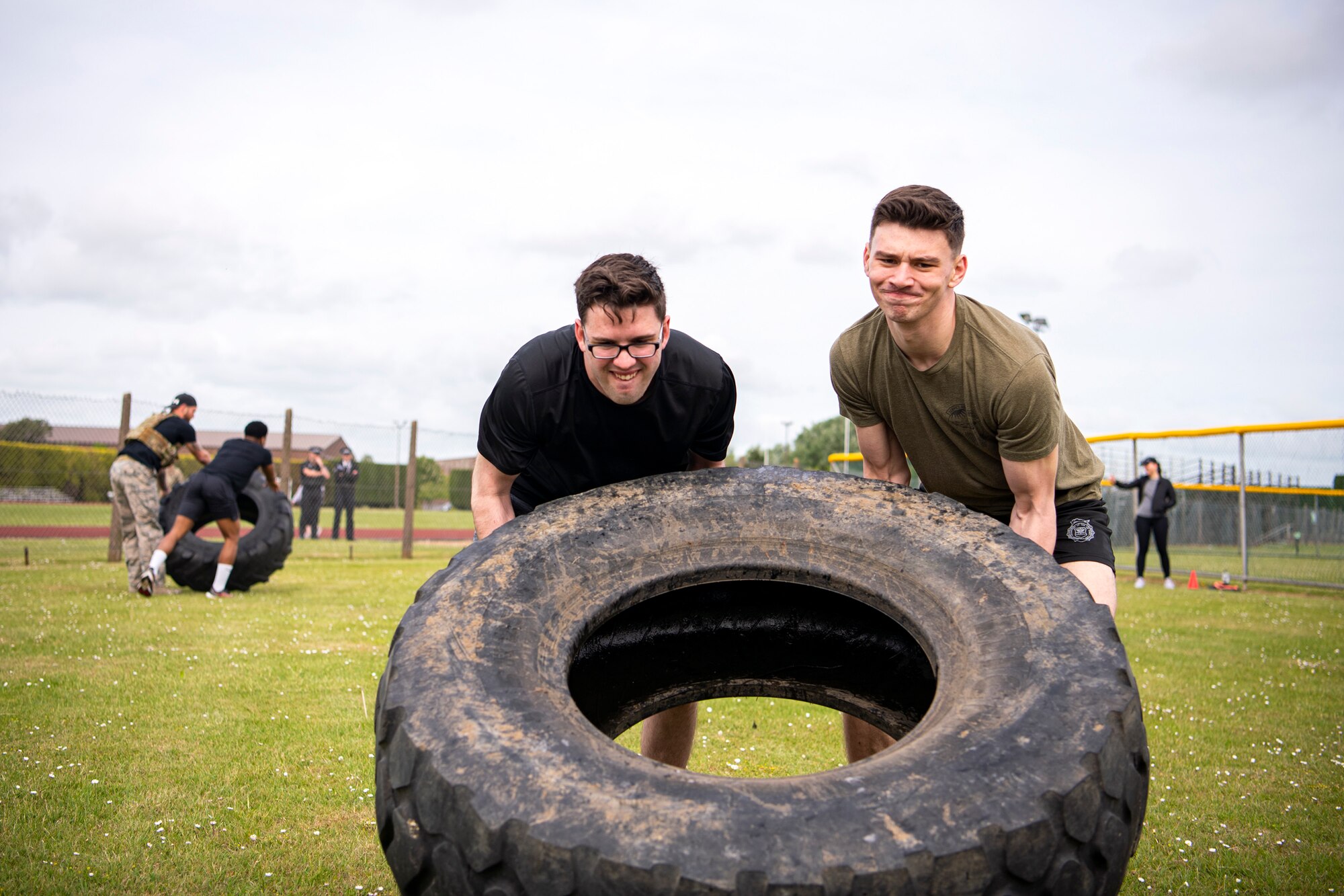 Airmen from the 423d Security Forces Squadron flip tires as part of a defender challenge at RAF Alconbury, May 18, 2022. Airmen, civilians and local law enforcement participated in the challenge, held in honor of National Police Week, to pay homage to those who gave their lives in the line of duty. (U.S. Air Force photo by Staff Sgt. Eugene Oliver)