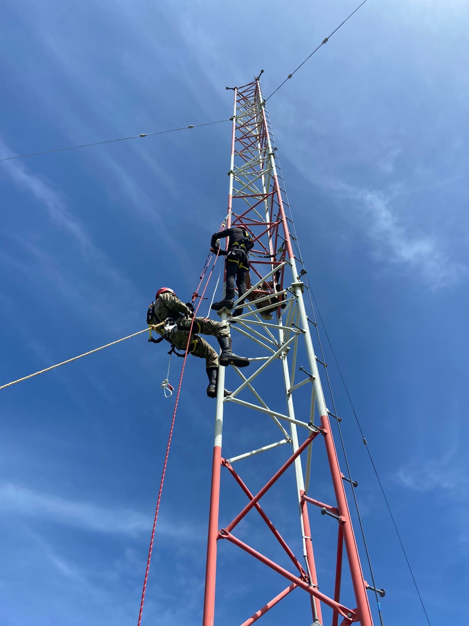 Two Airmen climbing an antenna tower.
