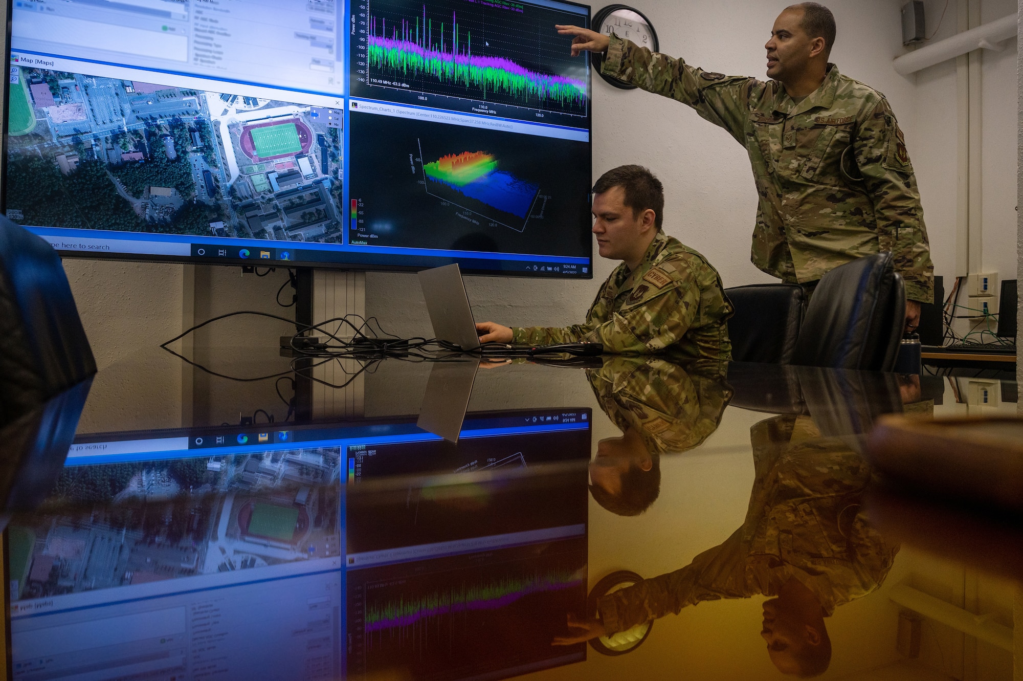 Two Airmen standing next to a projection screen in a conference room.