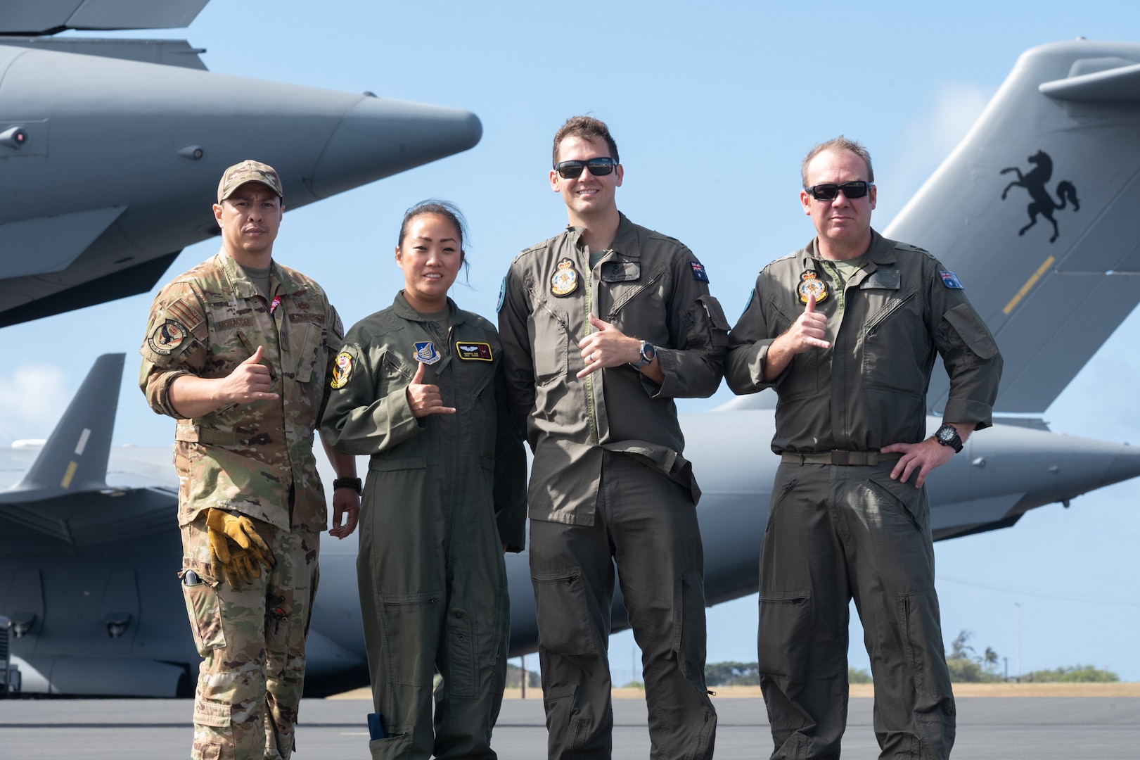 U.S. Air Force loadmasters from the 204th Airlift Squadron, Tech. Sgt. Josh Moracco and Senior Airman Sandra Kim, and Royal Australian Air Force loadmasters from 87 Squadron, Sgt. Ben Russell and Flt Sgt. Jay Johnson, gather May 12, 2022, at Joint Base Pearl Harbor-Hickam, Hawaii. Aircrew members from each nation shared responsibilities on one another’s aircraft throughout training exercise Global Dexterity.