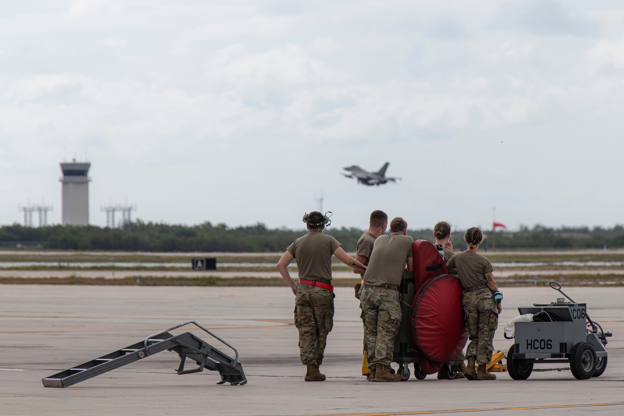 A group of Airmen watch an F-16 Fighting Falcon take off