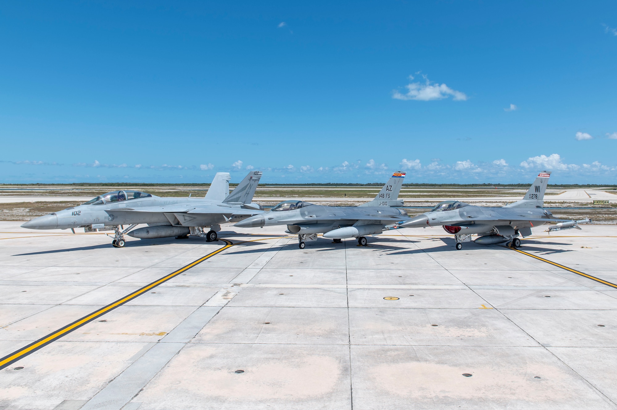 Joint U.S. military fighter jet aircraft are parked together on the flight line.