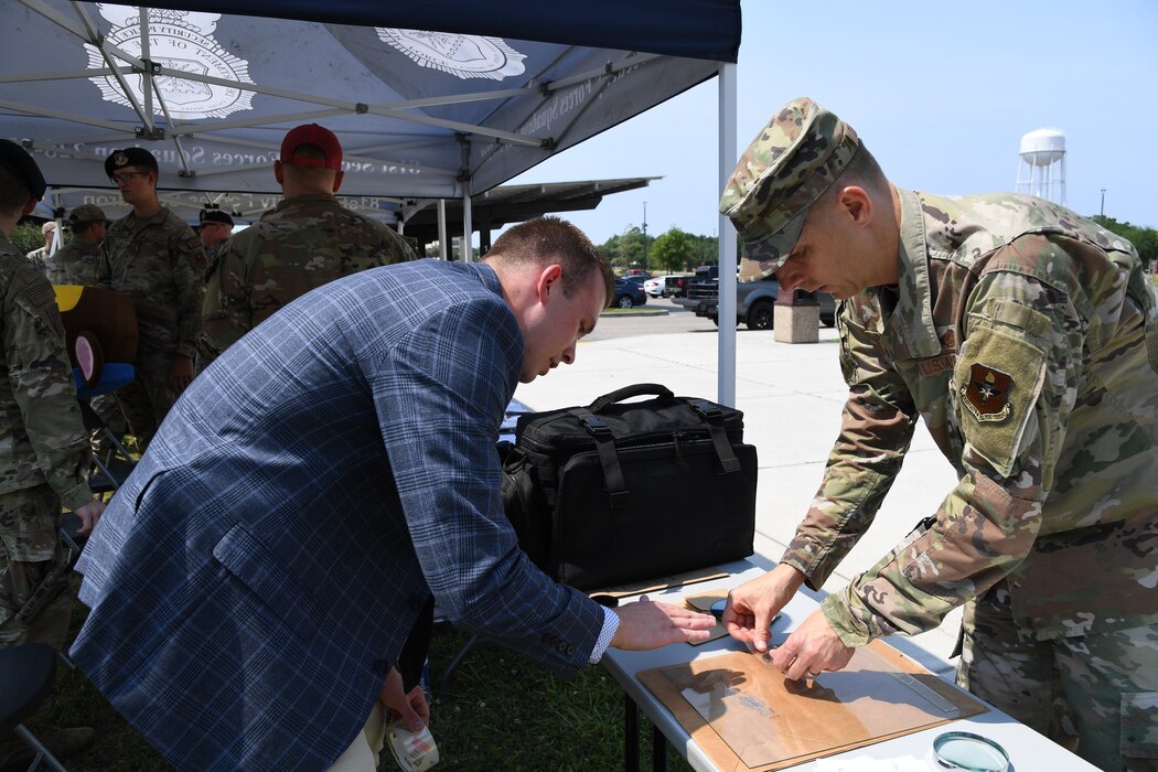 A U.S. Air Force Office of Special Investigations, Detachment 407, special agent assists Col. Ryan Crowley, 81st Mission Support Group commander, with capturing a finger print during Police Week defender demo day at Keesler Air Force Base, Mississippi, May 18, 2022. The event was held during National Police Week, recognizing the men and women in law enforcement. (U.S. Air Force photo by Kemberly Groue)