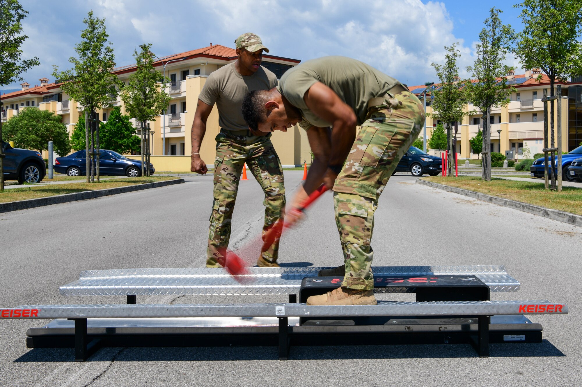 Airman 1st Class Jalyn Cash, 31st Civil Engineer Squadron Fire Department firefighter, strikes a sledge hammer on a Keiser FORCE Machine during the annual Guns and Hoses competition at Aviano Air Base, Italy, May 18, 2022. Airmen from the 31st Security Forces Squadron and 31st CES Fire Department competed in an obstacle course themed after challenges from their respective jobs in honor of Police Week. Police Week recognizes law enforcement, citizens and family survivors of law enforcement to pay special tribute to those who have lost their lives in the line of duty for the safety and protection of others. (U.S. Air Force photo by Senior Airman Brooke Moeder)
