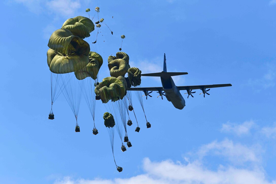 Packages attached to parachutes are dropped form an airborne aircraft.