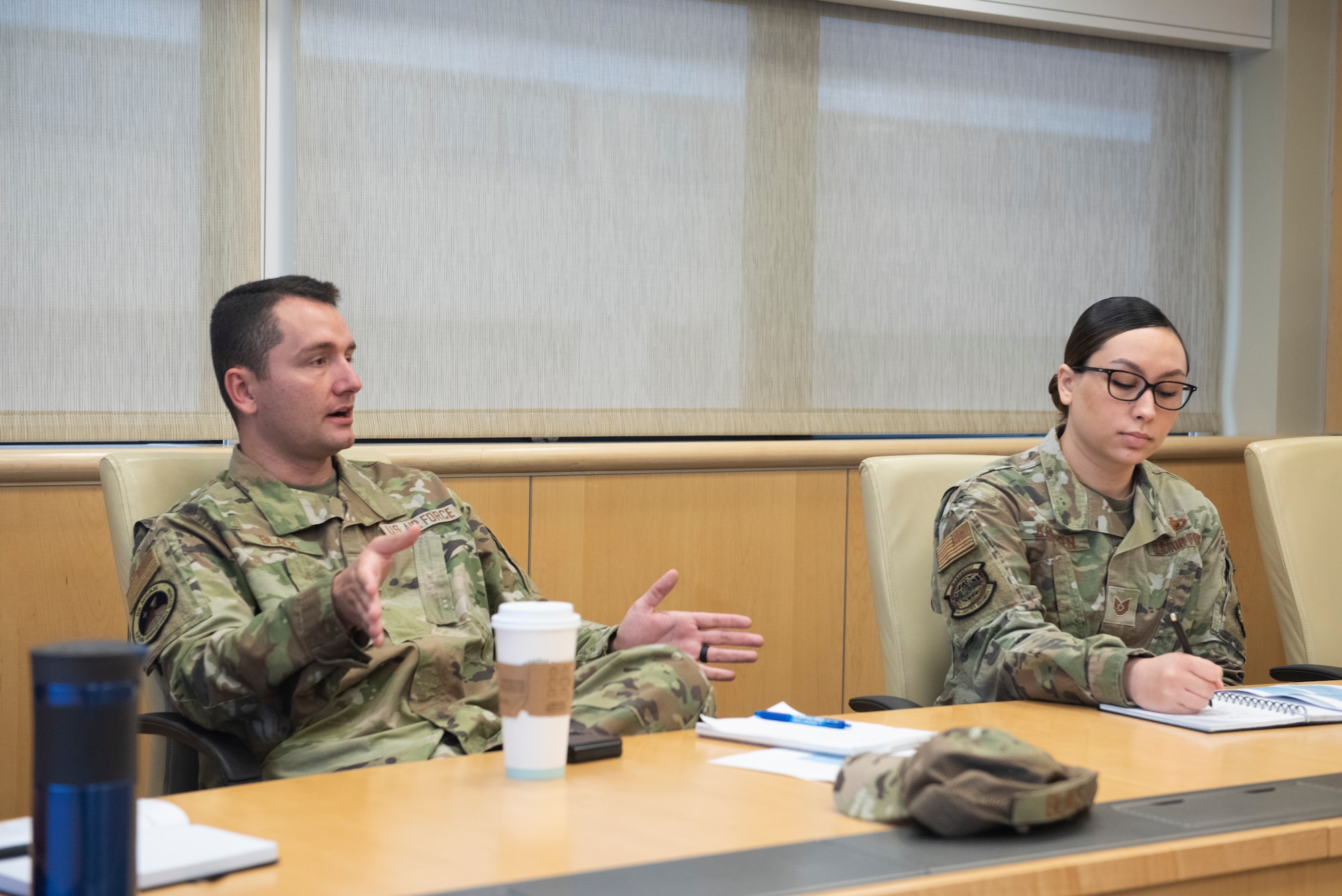 Man in uniform speaks as woman in uniform writes