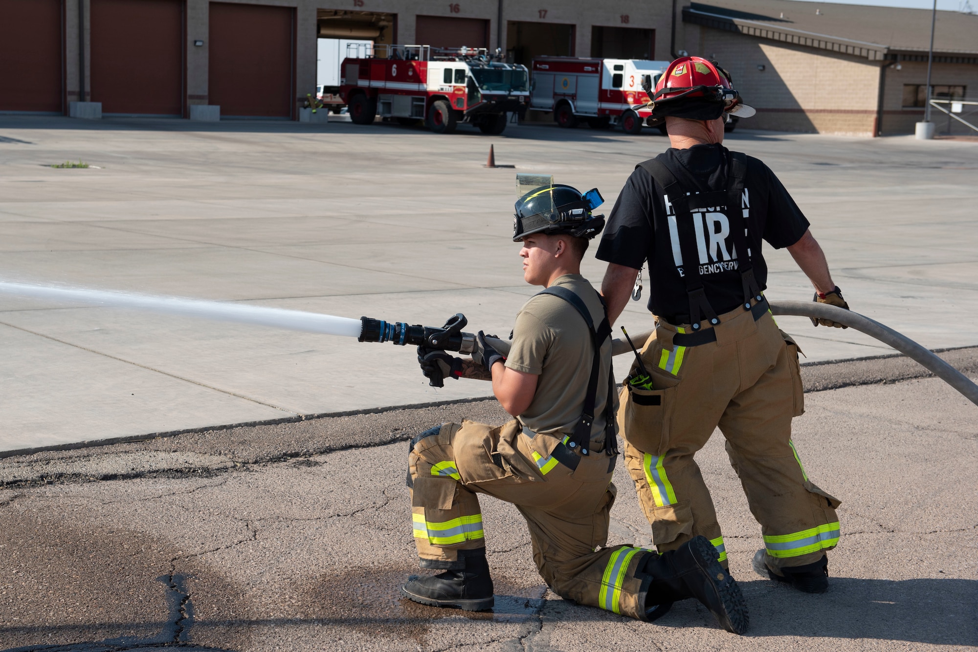 Norman Bloom (right), 49th Civil Engineer Squadron company officer and Airman 1st Class Jayden Zepeda (left), 49th CES firefighter, shoot water out of a hose during an emergency response training exercise, May 19, 2022, on Holloman Air Force Base, New Mexico.