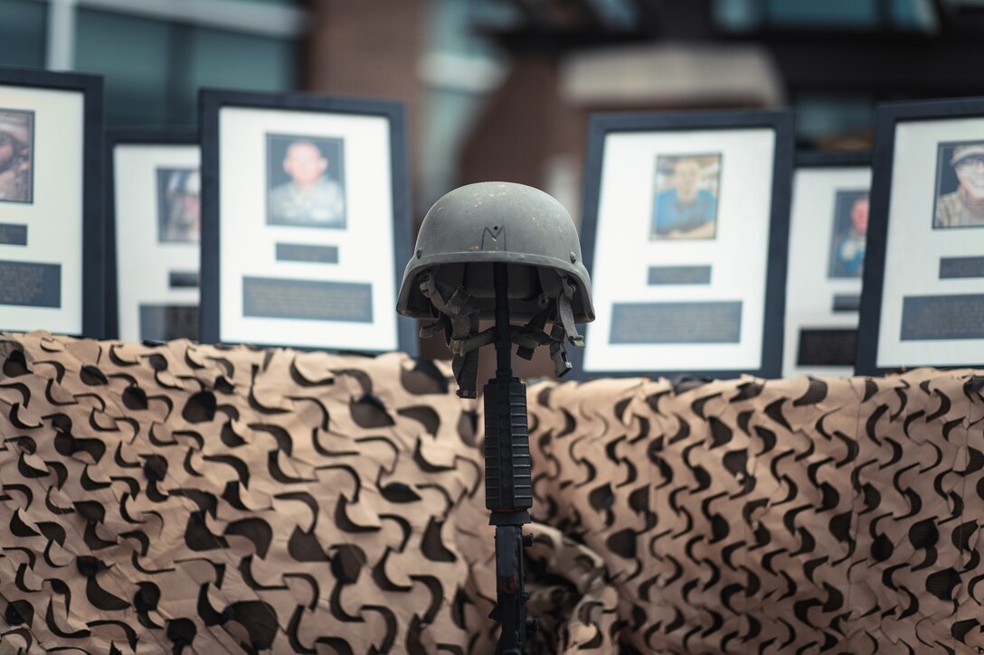 A Fallen Soldier Battlefield Cross sits on display in front of memorial photographs of fallen service members during an opening ceremony in honor of National Police Week at Joint Base Andrews, Md., May 16, 2022. During the ceremony, Col. Victor Moncrieffe II, Air National Guard Security Forces director, discussed the importance of law enforcement officers and observed a moment of silence in homage to fallen service members. (U.S. Air Force photo by Senior Airman Bridgitte Taylor)