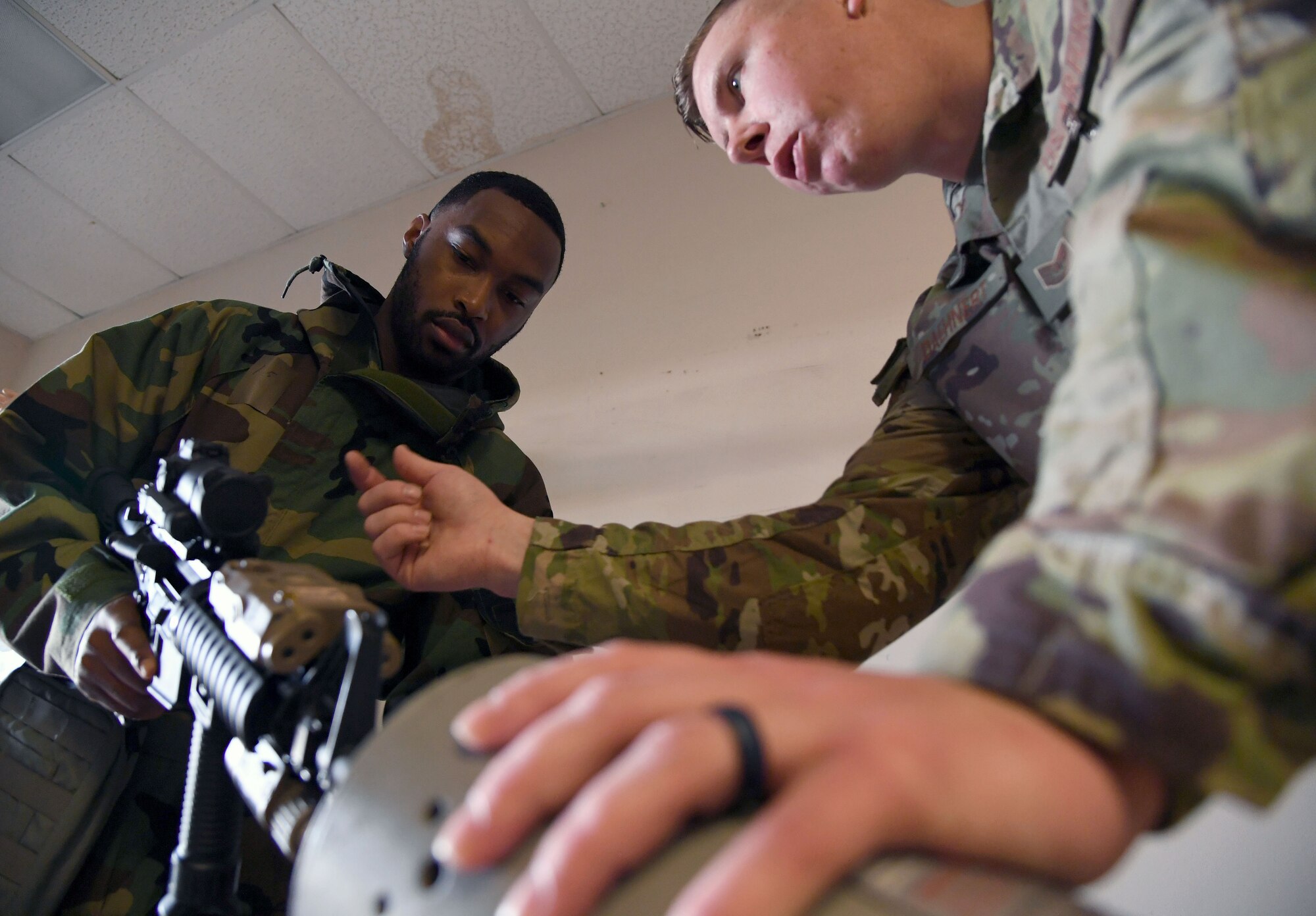 U.S. Air Force Tech. Sgt. Michael Daehnert, 81st Security Forces Squadron combat arms noncommissioned officer in charge, assists Staff Sgt. Chardarius Alex, Second Air Force command support staff technician, with weapons handling assessment during a small scale readiness assessment at Keesler Air Force Base, Mississippi, May 18, 2022. The assessment allowed Keesler personnel to be evaluated on their basic life saving skills in preparation of real-world events. (U.S. Air Force photo by Kemberly Groue)