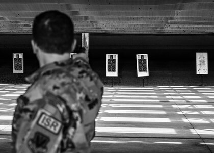 A participant of the 633d Security Forces Squadron Excellence in Competition tournament fixes his stance as he prepares to fire one-handed at Joint Base Langley-Eustis, Virginia, May 19, 2022.