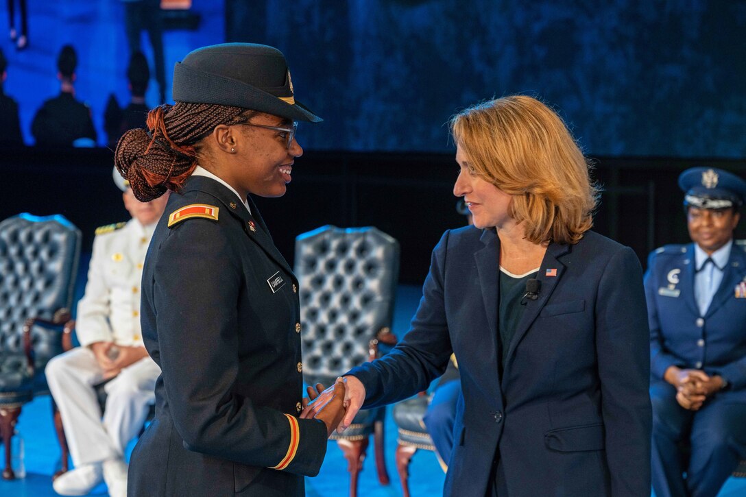 Deputy Secretary of Defense Kathleen H. Hicks shakes hands with a graduate.