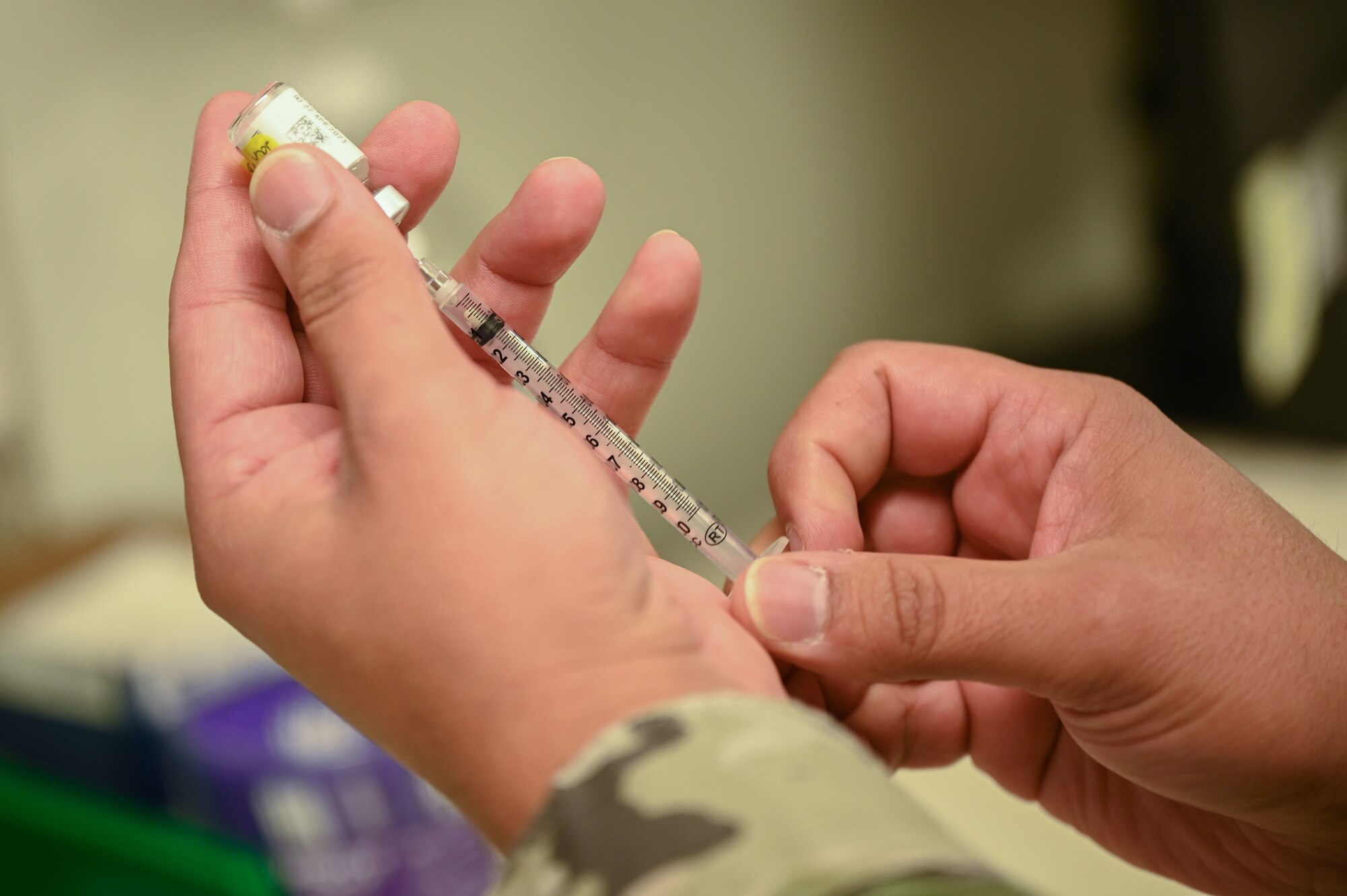 Someone draws fluid into a syringe.