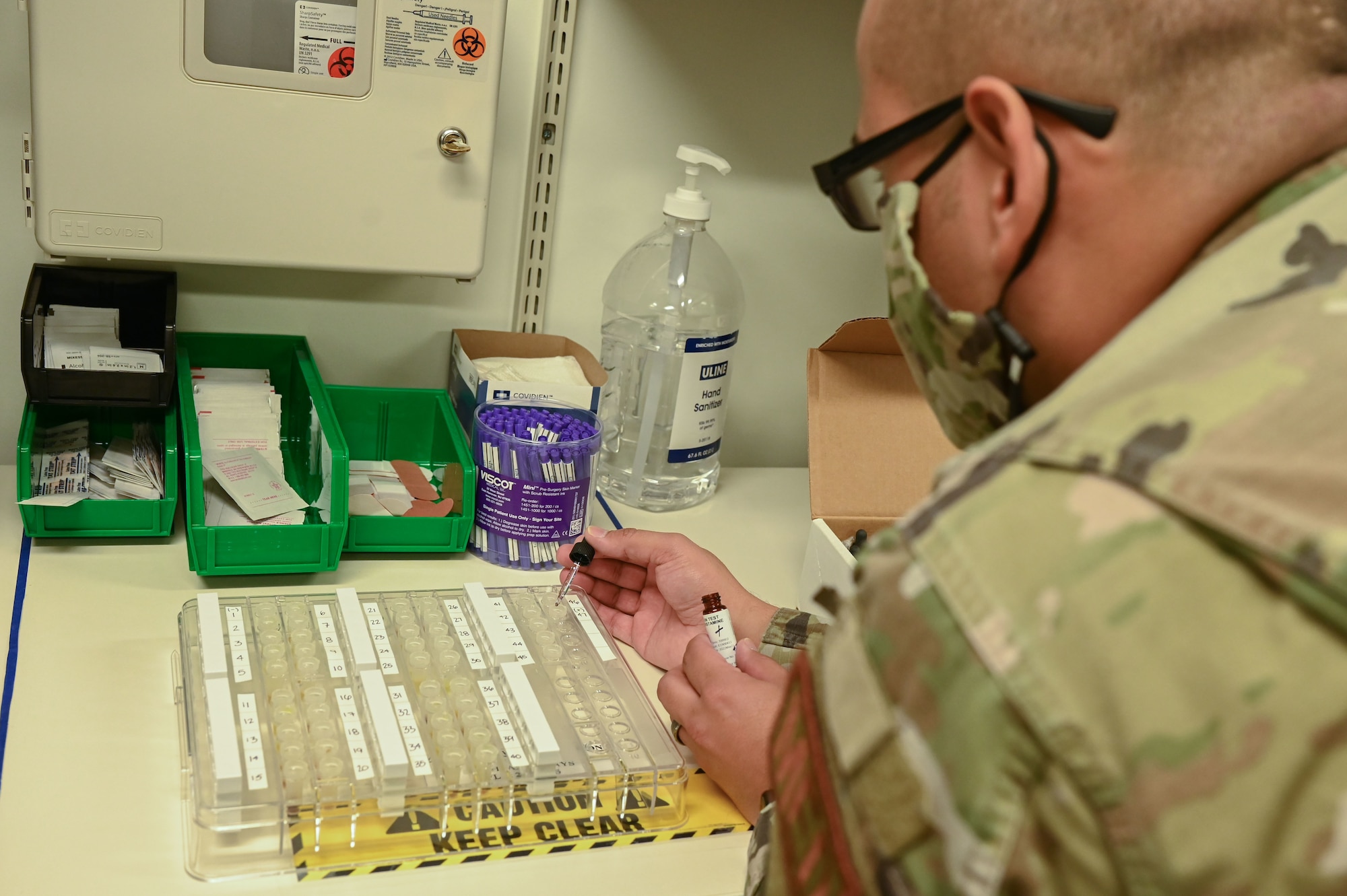 A man squirts fluid out of a syringe into a pallet.