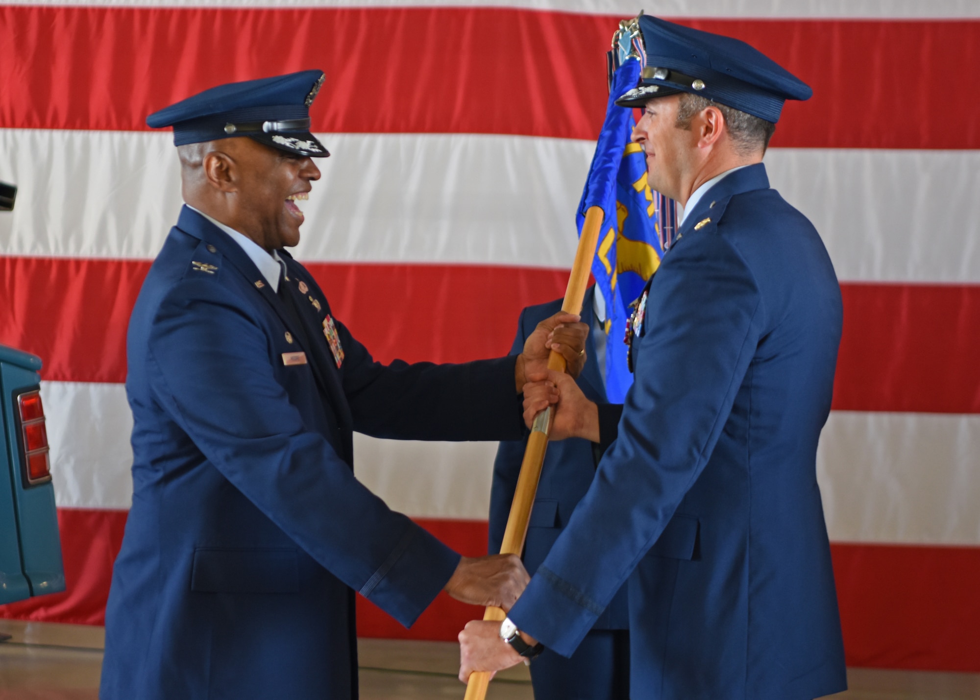 U.S. Air Force Maj. Joseph Freeman, 17th Logistics Readiness Squadron outgoing commander, (right) relinquishes command to Col. Eugene Moore III, 17th Mission Support Group commander, during the 17th LRS change of command ceremony at Goodfellow Air Force Base, Texas, May 20, 2022. Passing the guidon physically represents the symbolism of passing the squadron responsibilities to the next commander. (U.S. Air Force photo by Senior Airman Ethan Sherwood)