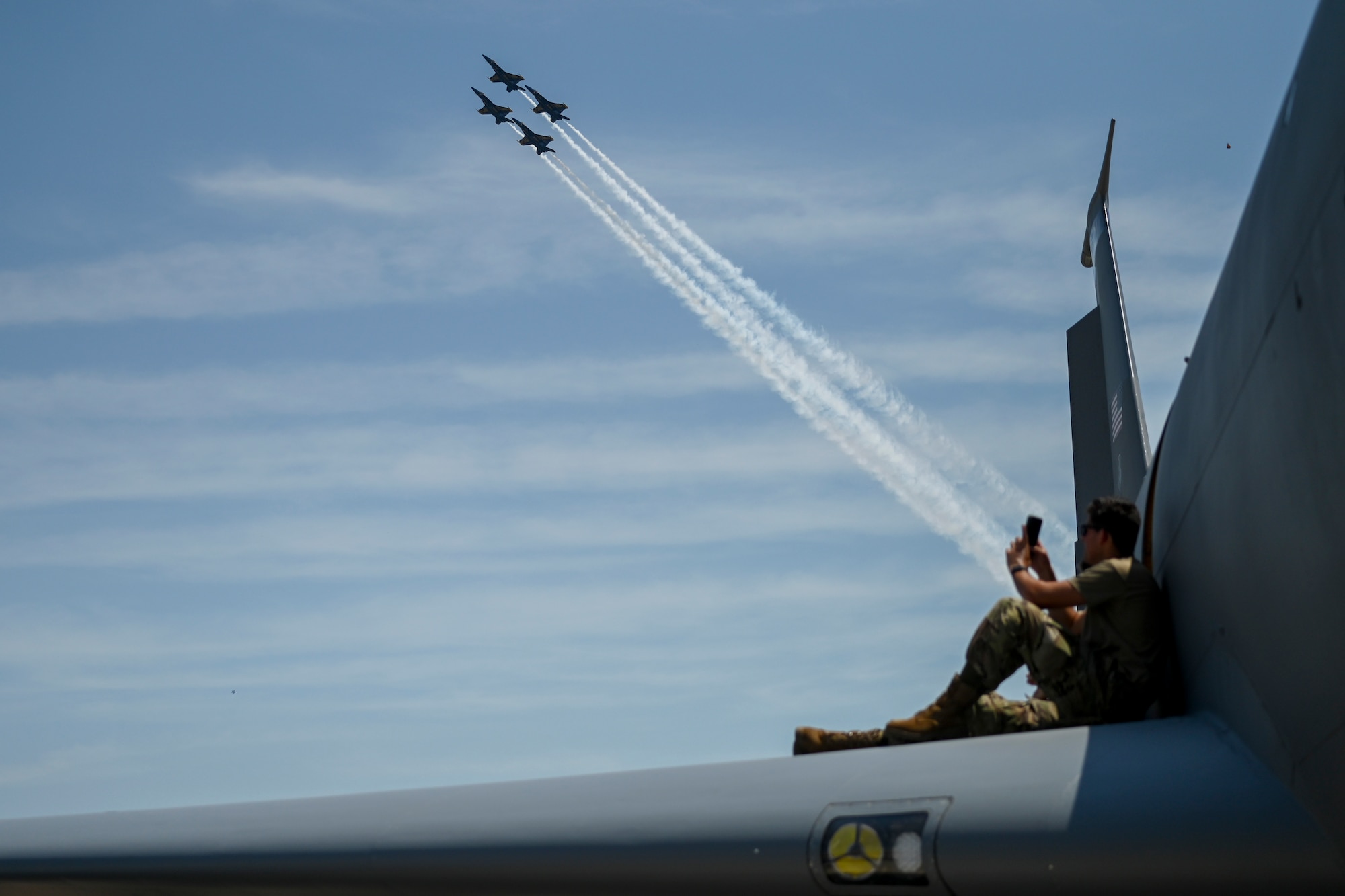 An Airman records the U.S. Navy Blue Angels demonstration team from the wing of an aircraft during day one of the 2022 Thunder Over Dover Airshow, May 21, 2022, at Dover Air Force Base, Delaware. This was the first time the Blue Angels performed at Dover AFB since 1991. (U.S. Air Force photo by Staff Sgt. Sabatino DiMascio)