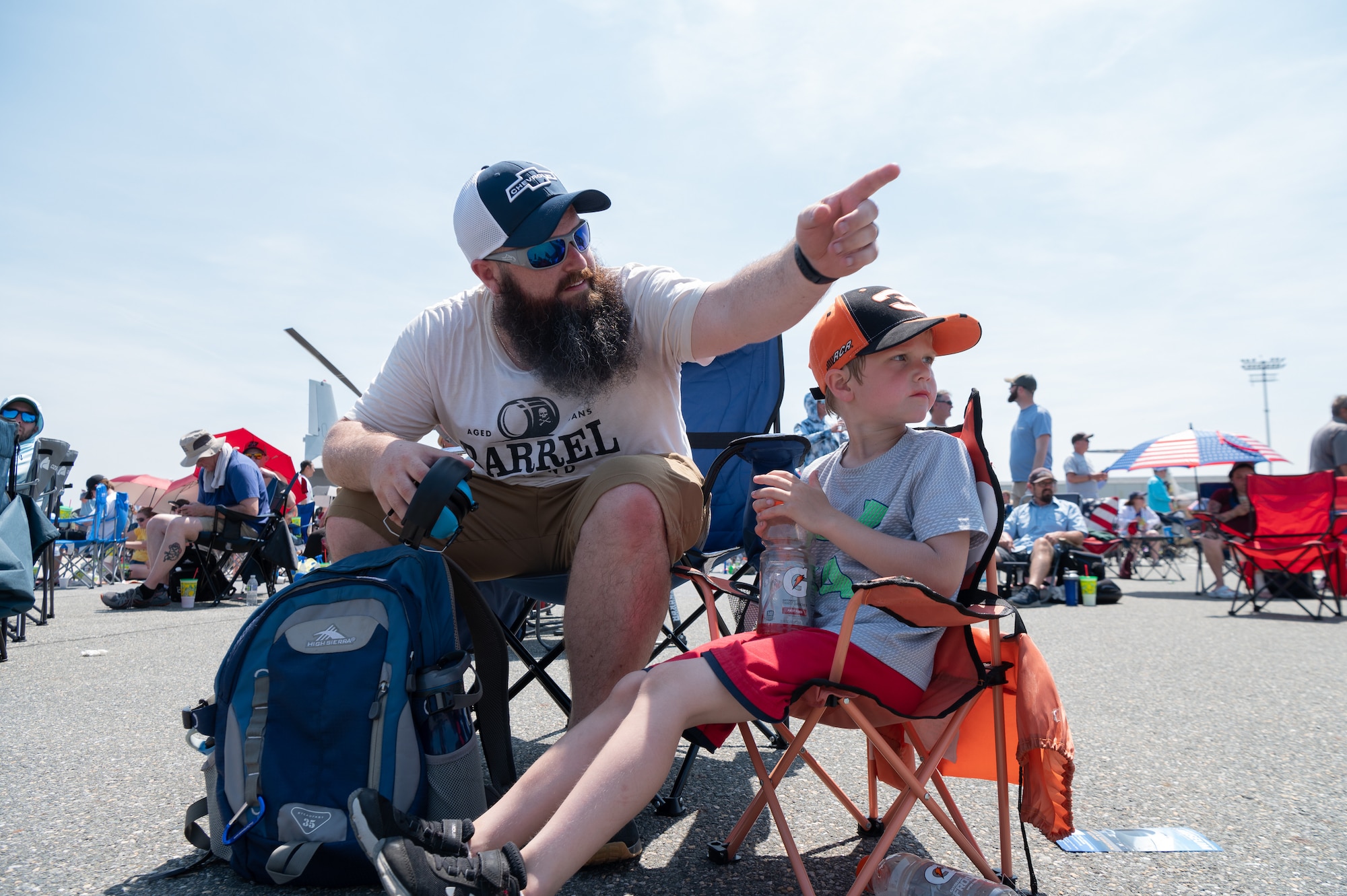 Chris Tacchi points to a C-17 Globemaster III flying over the crowd, during the first day of the 2022 Thunder Over Dover Airshow, May 21, 2022, at Dover Air Force Base, Delaware. The base opened its gates to the public for a free, two-day event to showcase the Air Force and the base’s mission of providing rapid global airlift every day of the year. (U.S. Air Force photo by Mauricio Campino)