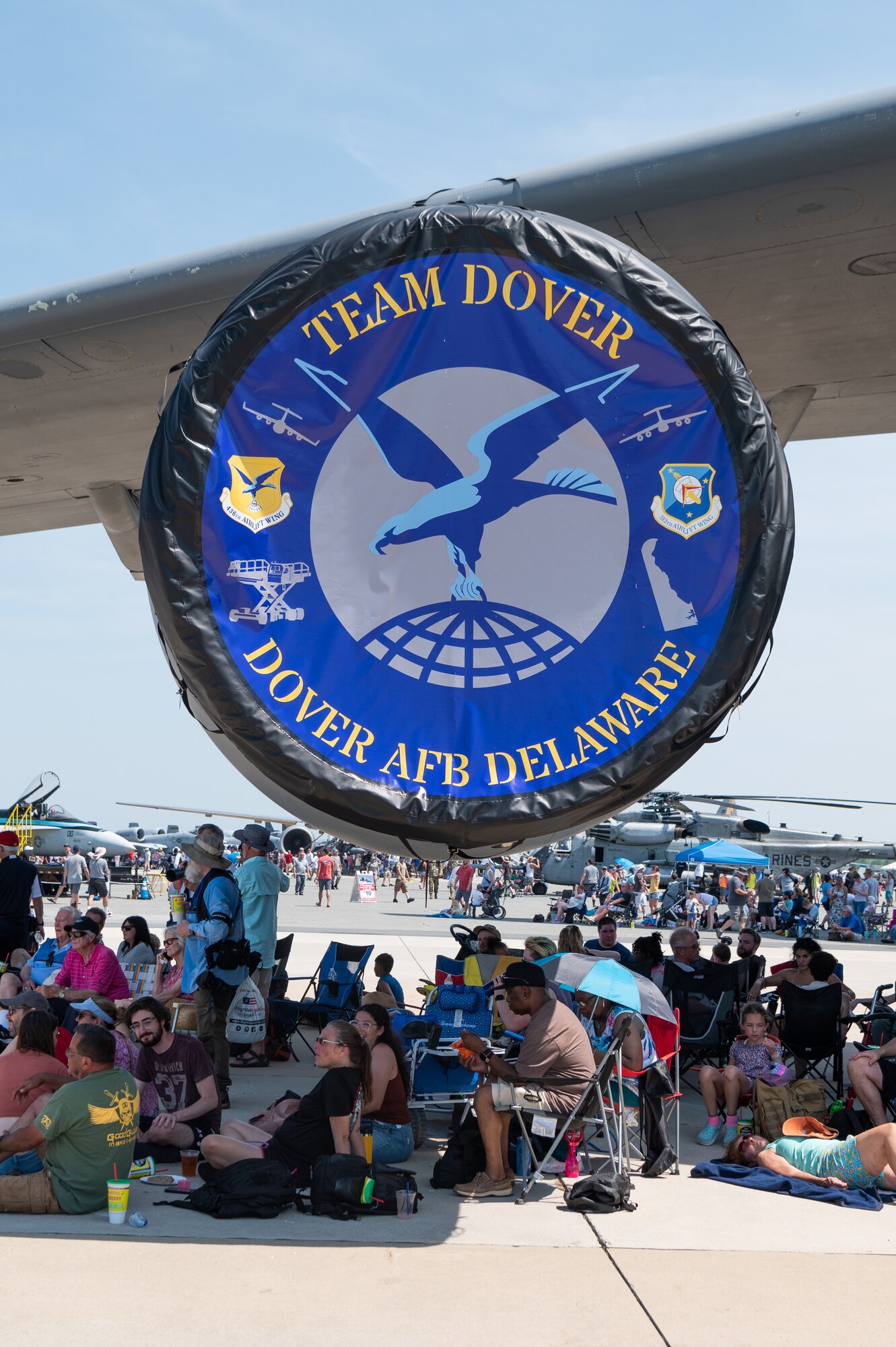 Spectators sit in the shade under the wing of a C-5M Super Galaxy during day one of the 2022 Thunder Over Dover Airshow, May 21, 2022, at Dover Air Force Base, Delaware. The base opened its gates to more than 40,000 spectators for a free, two-day event to showcase the Air Force and the base’s mission of providing rapid global airlift every day of the year. (U.S. Air Force photo by Mauricio Campino)