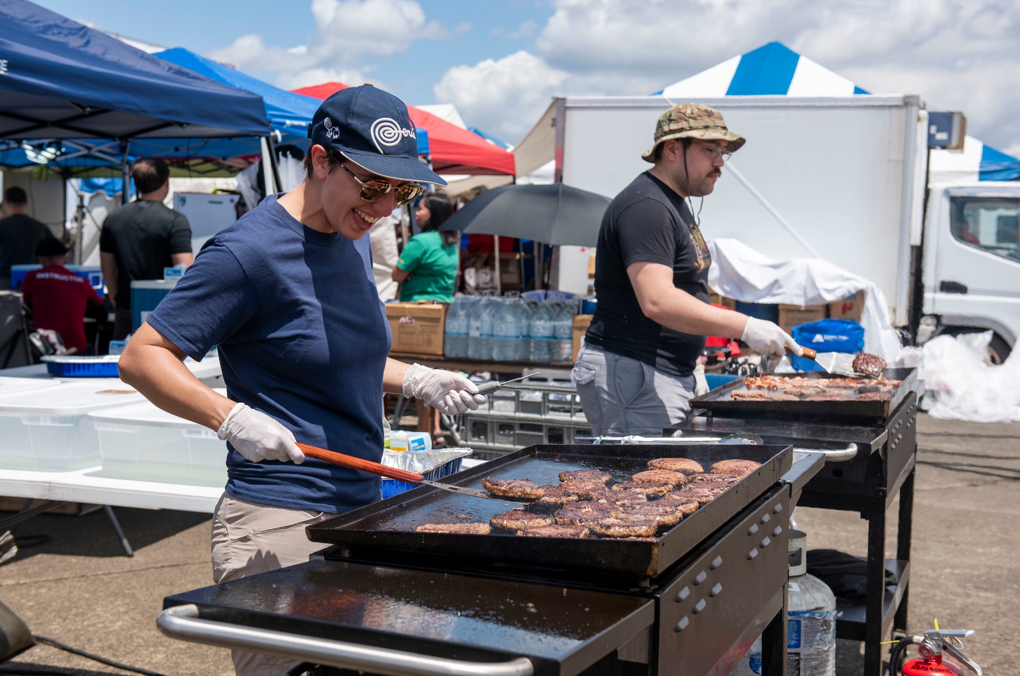 Volunteers flip burgers on a grill during Friendship Festival 2022, at Yokota Air Base, Japan May 22, 2022. The two-day festival was an opportunity for visitors to learn more about the U.S. and Japan bilateral partnership, while strengthening the bonds between Yokota and the local communities. Yokota was able to host the event with the support of Japanese Self-Defense Force, sister services and the local community. (U.S. Air Force photo by Senior Airman Hannah Bean)
